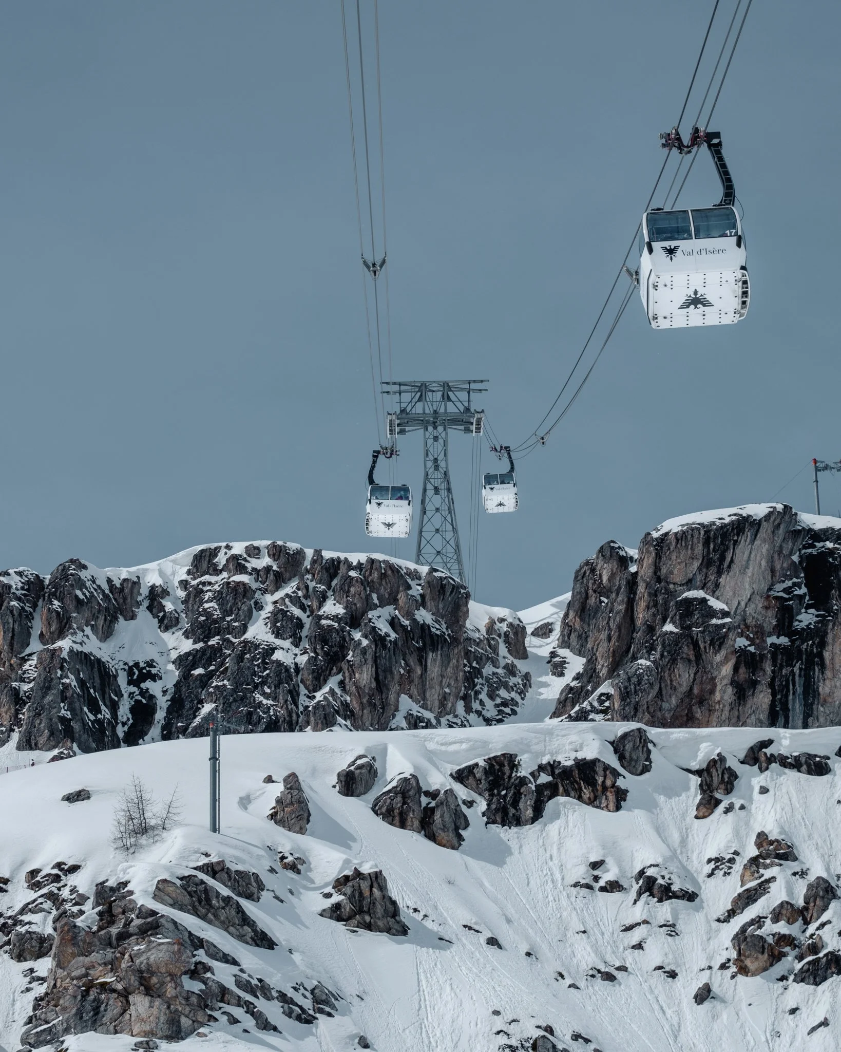 Cable cars above snow-covered cliffs in Val d’Isère