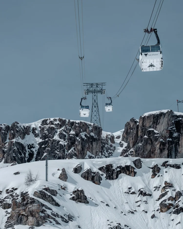 Cable cars above snow-covered cliffs in Val d’Isère