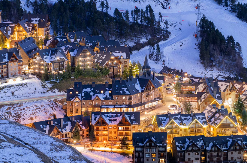 Snow-covered Baqueira village lit up at dusk in the Spanish Pyrenees