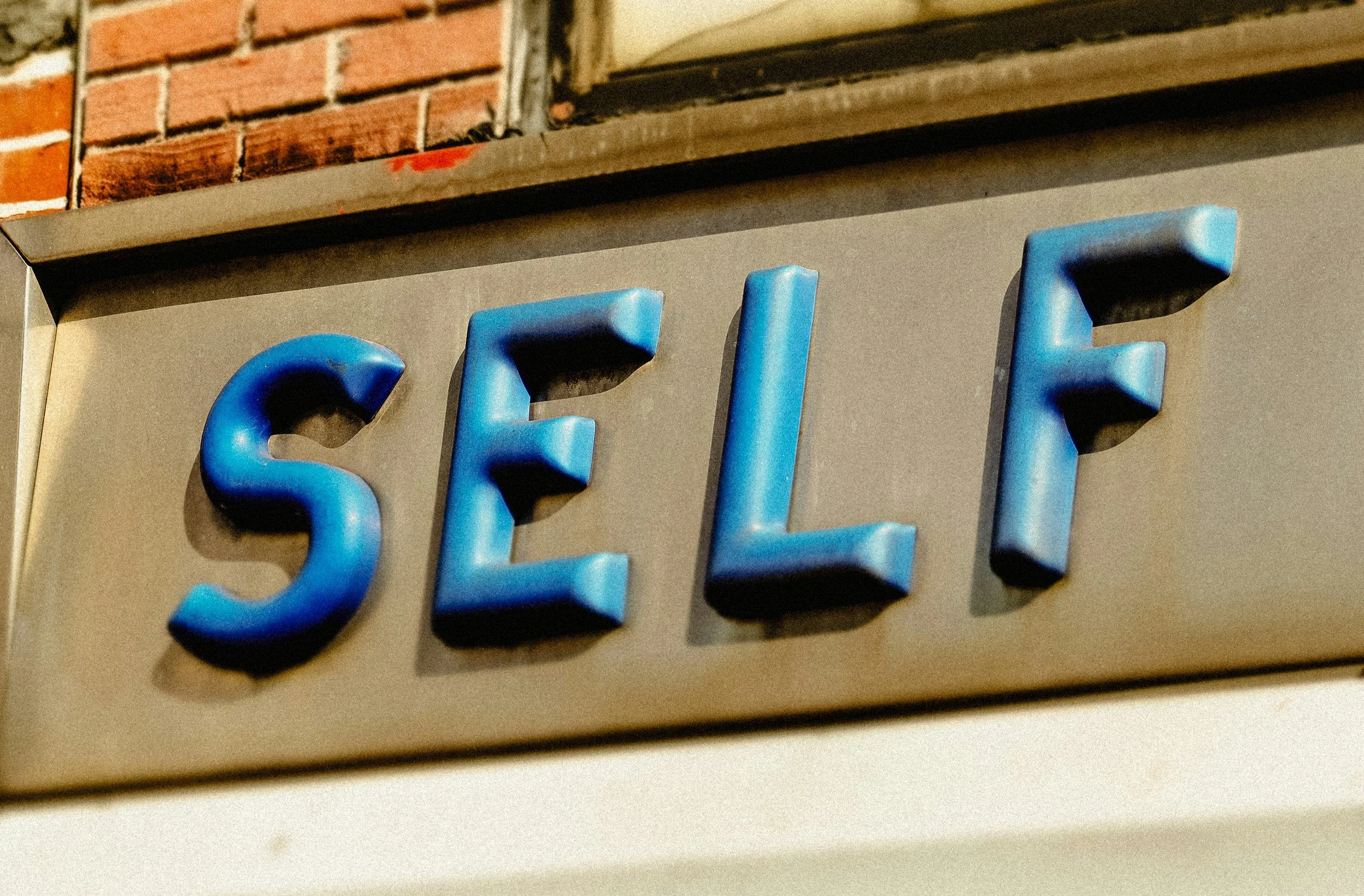 Nahaufnahme eines blauen Schildes mit den Lettern "Self" an der Seite eines Gebäudes
