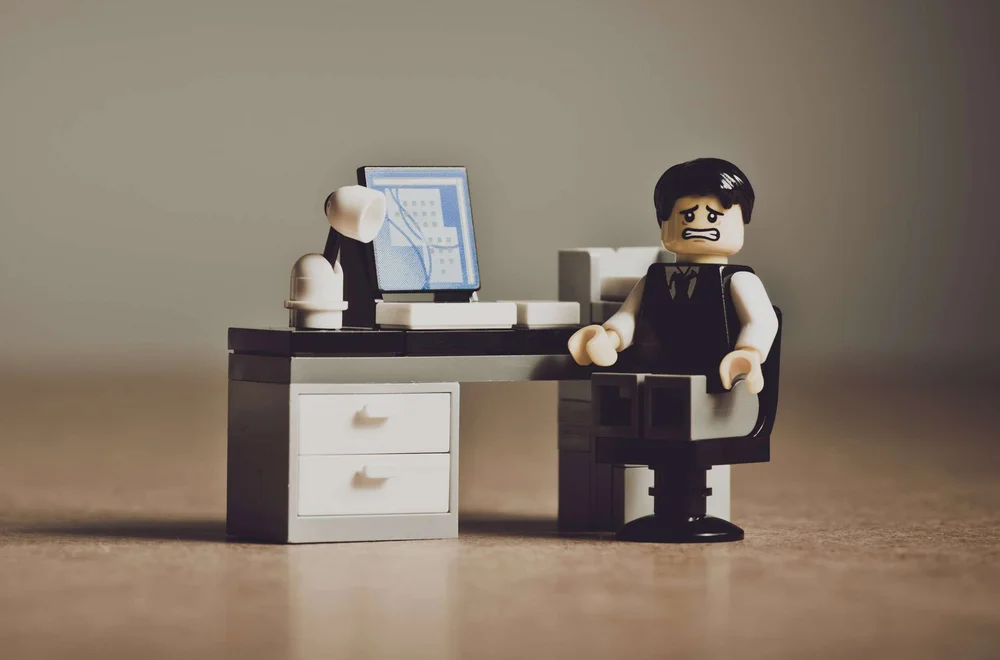 A stressed Lego office worker at his desk, overwhelmed by accounting paperwork