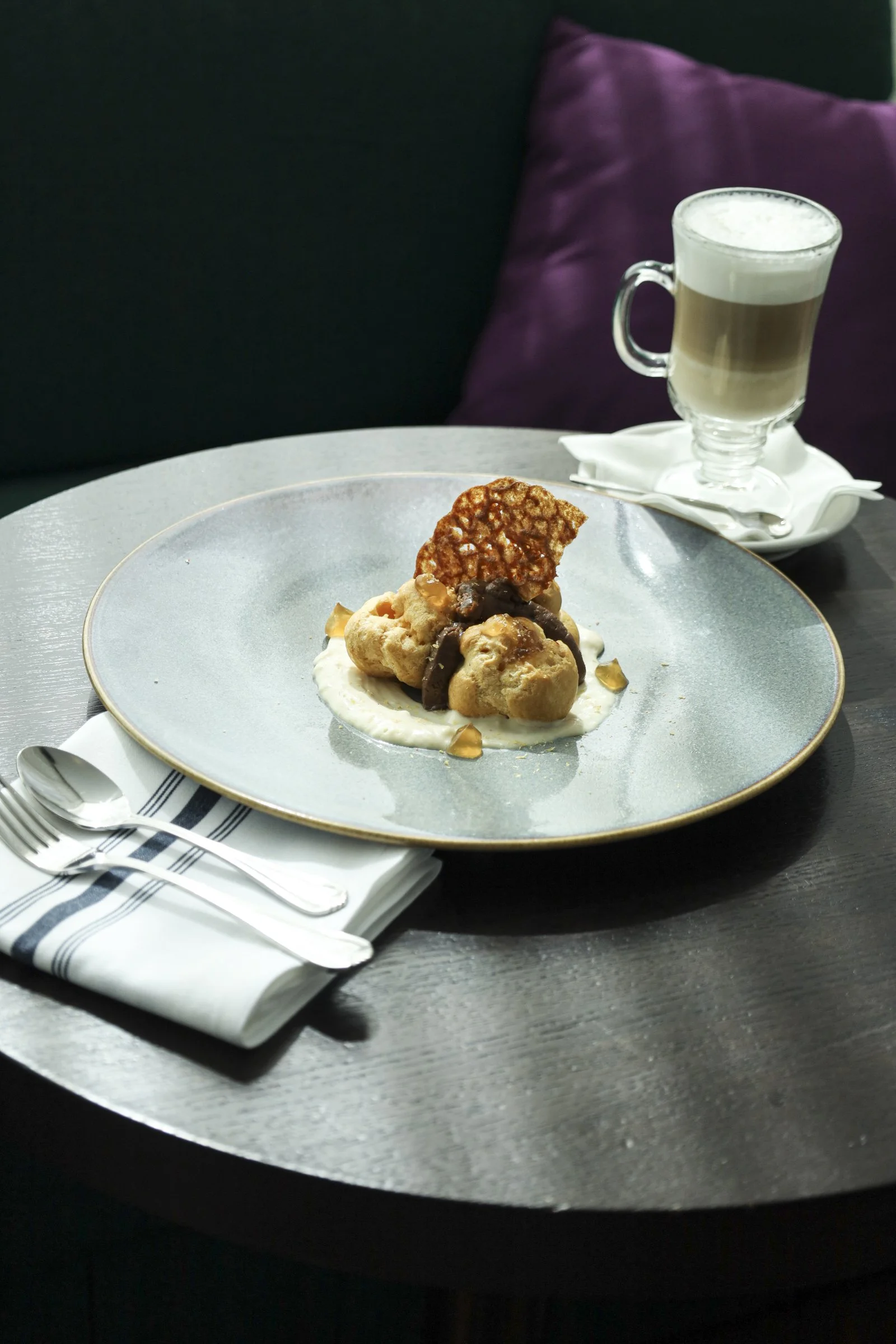 Gourmet profiteroles with caramel sauce and cream, served with a latte at a British pub Montreal in the heart of Old Montreal, offering a cozy Montreal bar atmosphere and authentic Montreal local atmosphere.