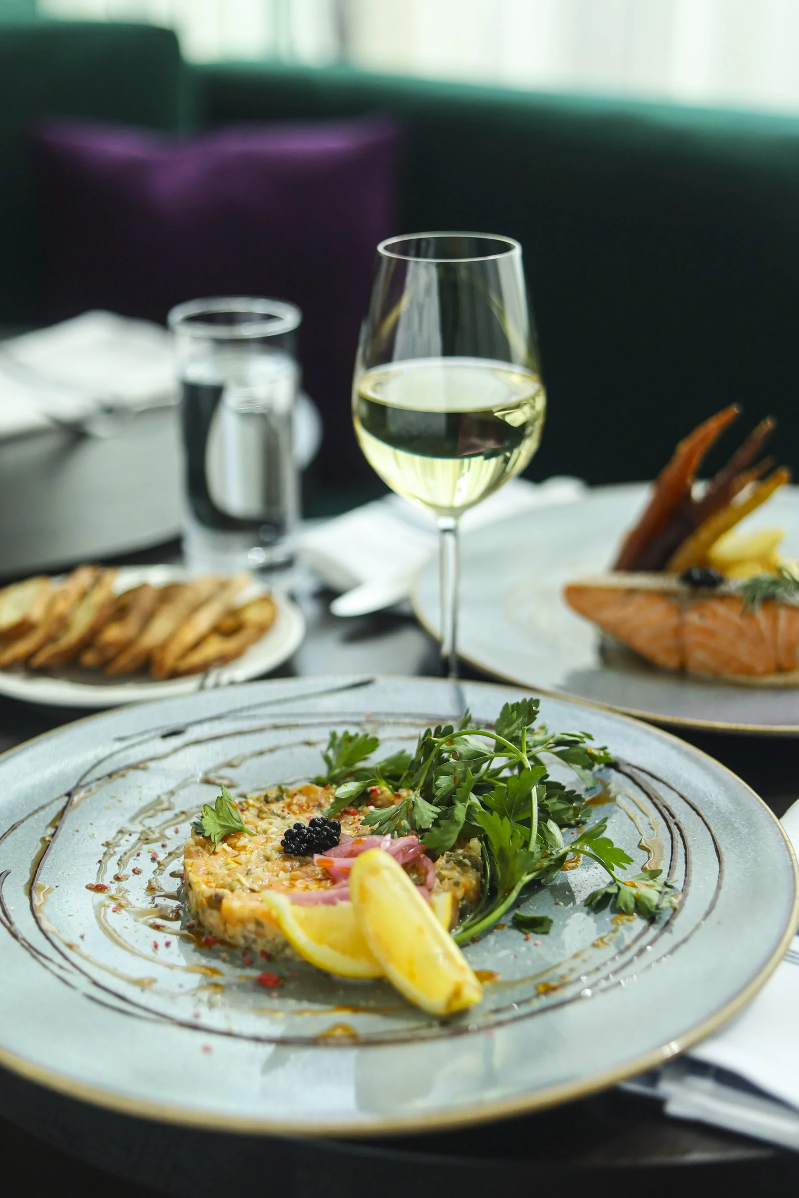 Salmon tartare with fresh herbs and lemon, served with white wine in a warm Montreal bar atmosphere at a Montreal restaurant in Old Montreal, offering an authentic Old Montreal pub dining experience.