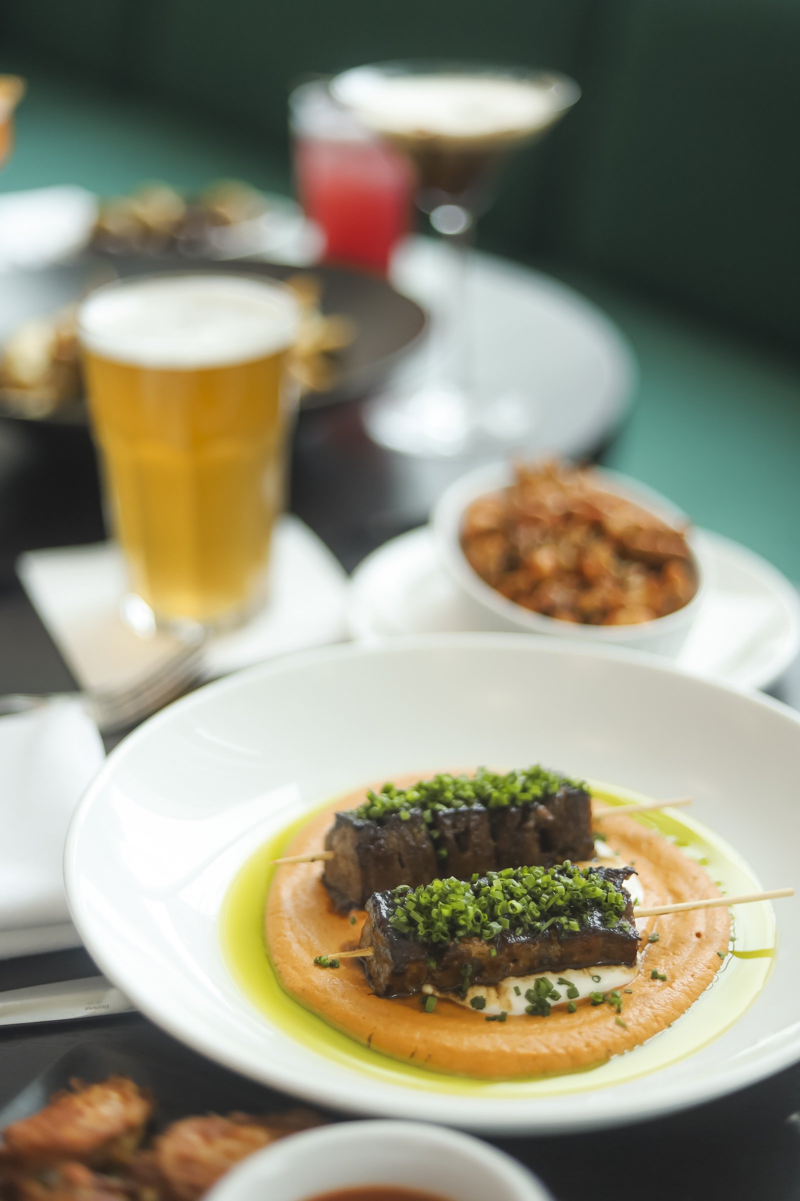 Grilled lamb skewers served with craft beer and cocktails at a British pub Montreal in Old Montreal, showcasing the vibrant Montreal bar atmosphere and refined Montreal restaurant Old Montreal dining experience.