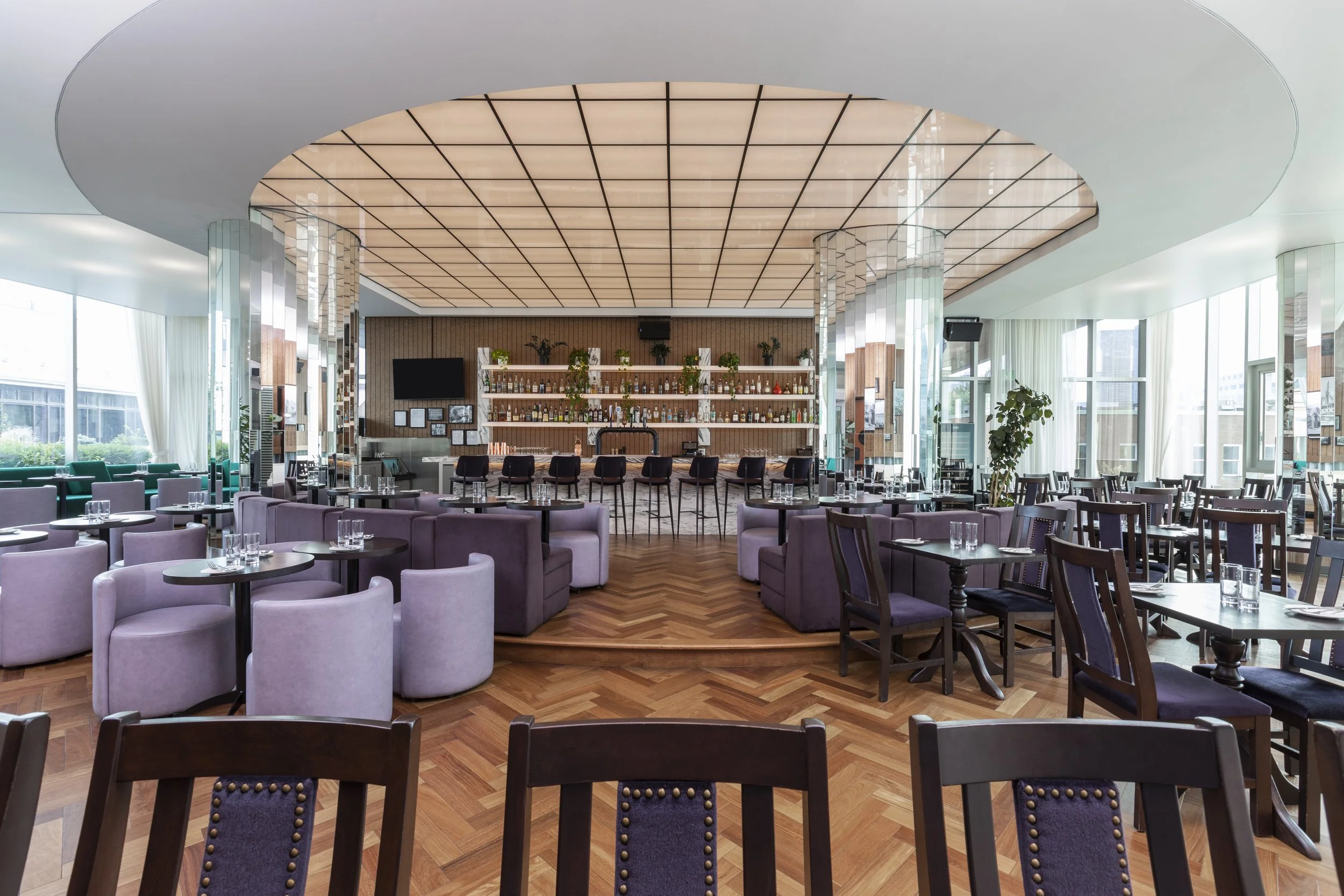 Spacious dining room with central bar, high ceilings, and elegant seating at a British pub Montreal in Old Montreal, showcasing the vibrant Montreal bar atmosphere and refined Montreal restaurant Old Montreal experience.