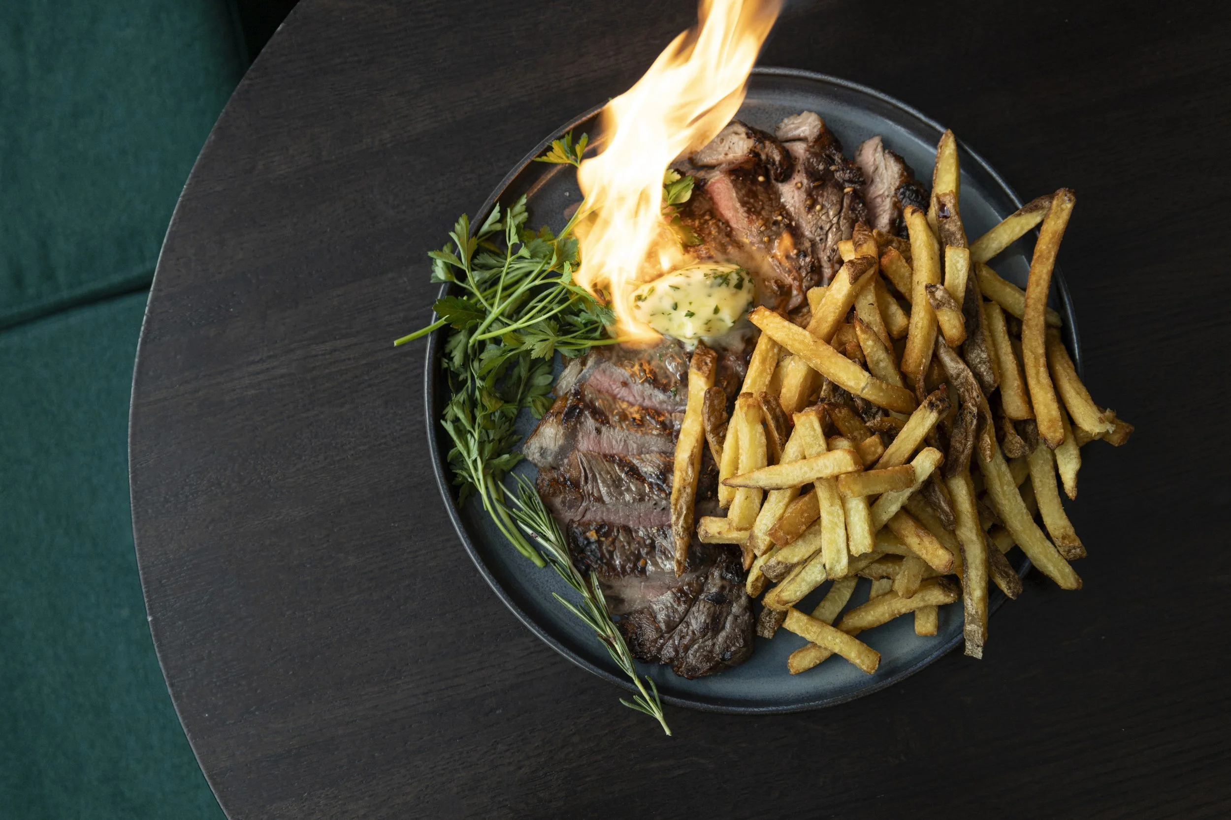Flambé steak frites with herb butter and crispy fries served at a British pub Montreal in Old Montreal, capturing the bold flavors and lively Montreal bar atmosphere of a classic Old Montreal pub.