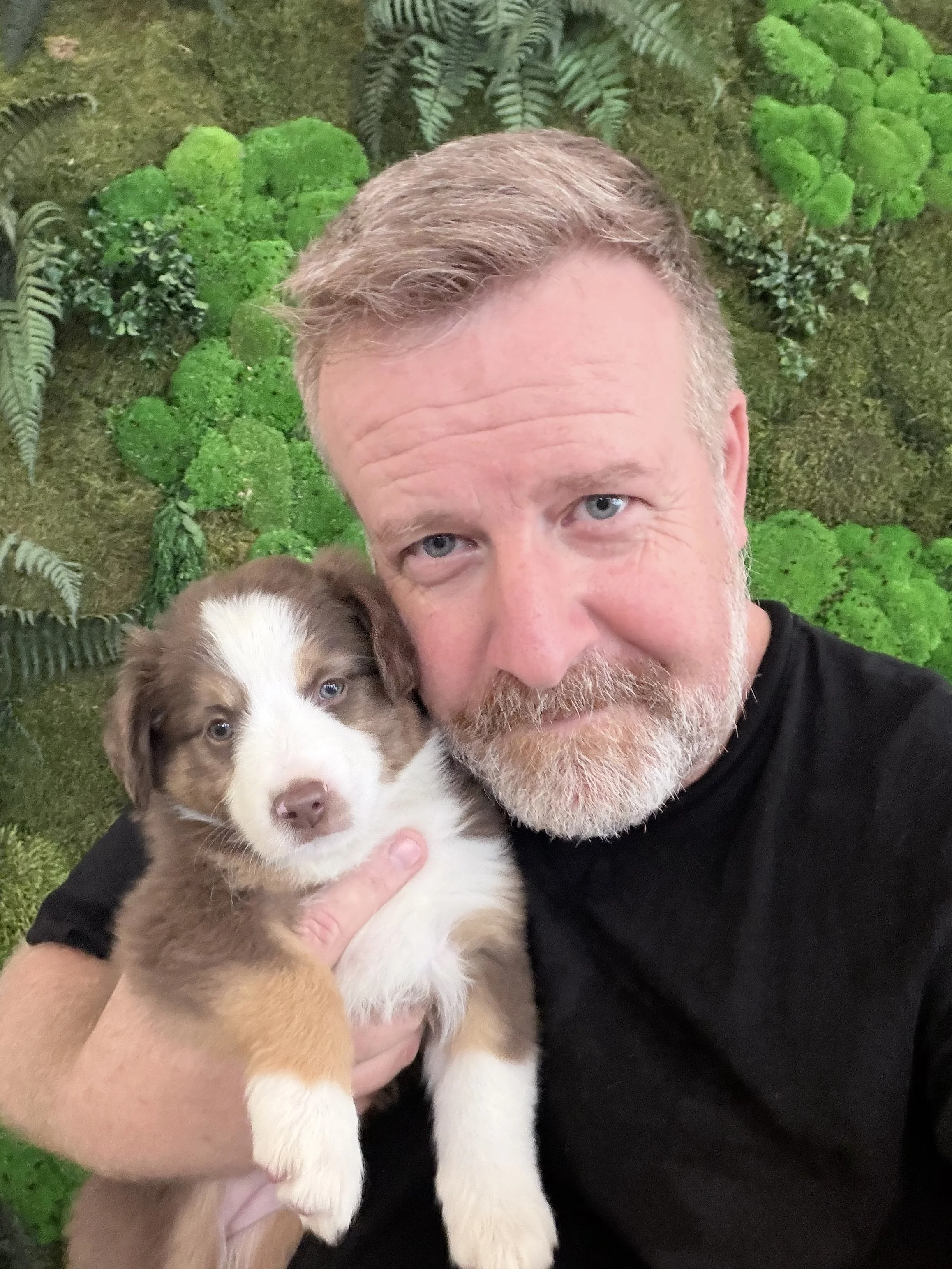 Steve Gouws holding a puppy with green background.jpg