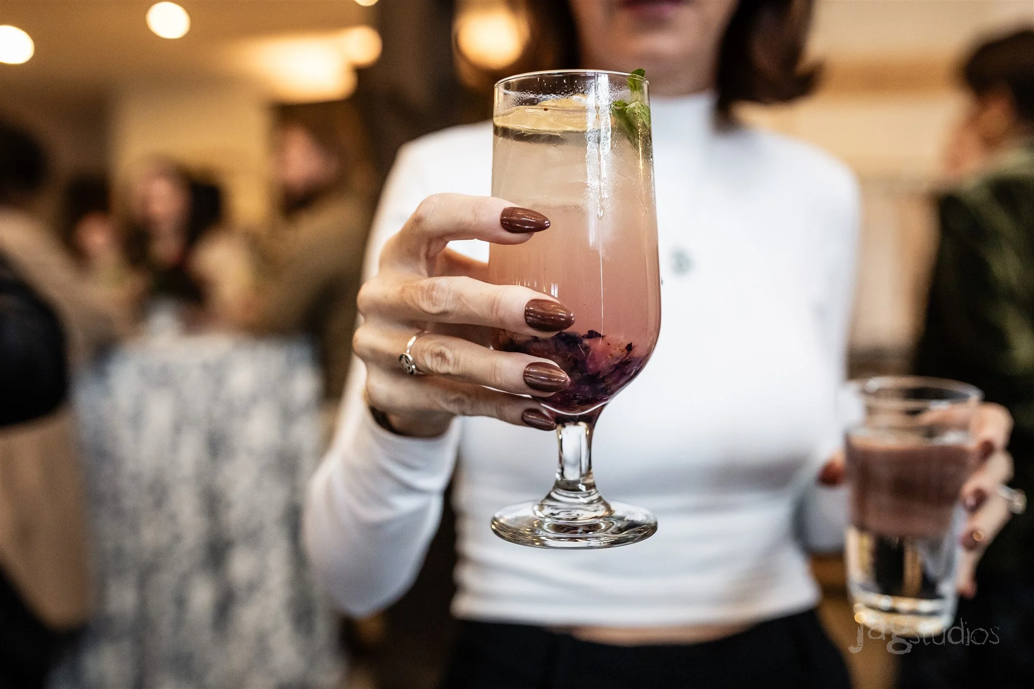 Person holding a blueberry mule cocktail with garnishes in a glass at a social gathering that Eido Bar Company bartended.