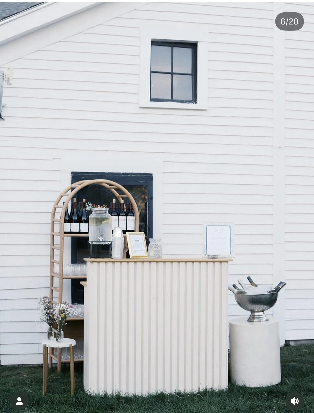 Wine bottles on a wooden bar setup, glasses and people in the background.