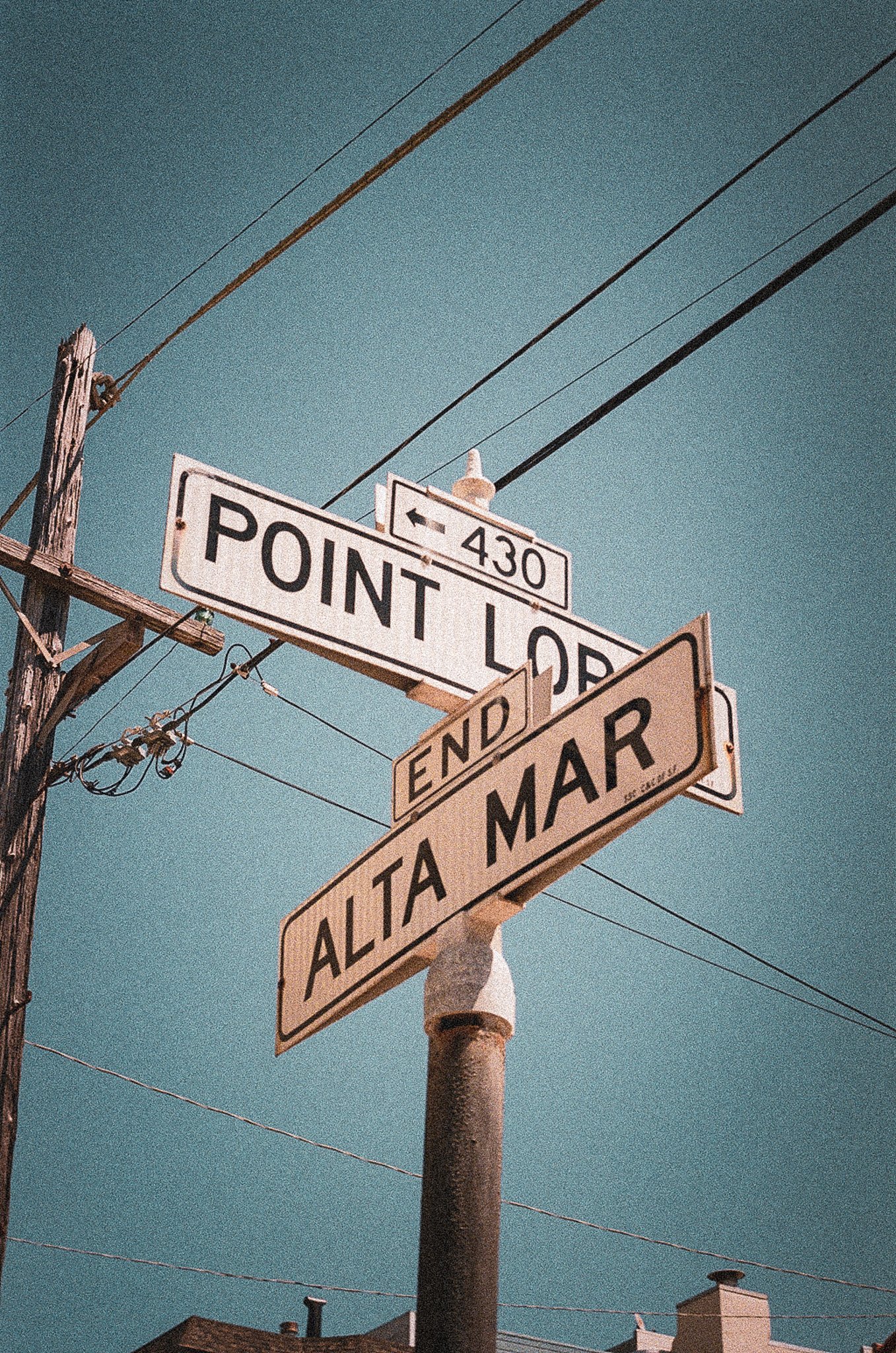 Street signs on a utility pole at Point Lobos, indicating the end of Alta Mar Avenue. The sky is clear and blue.