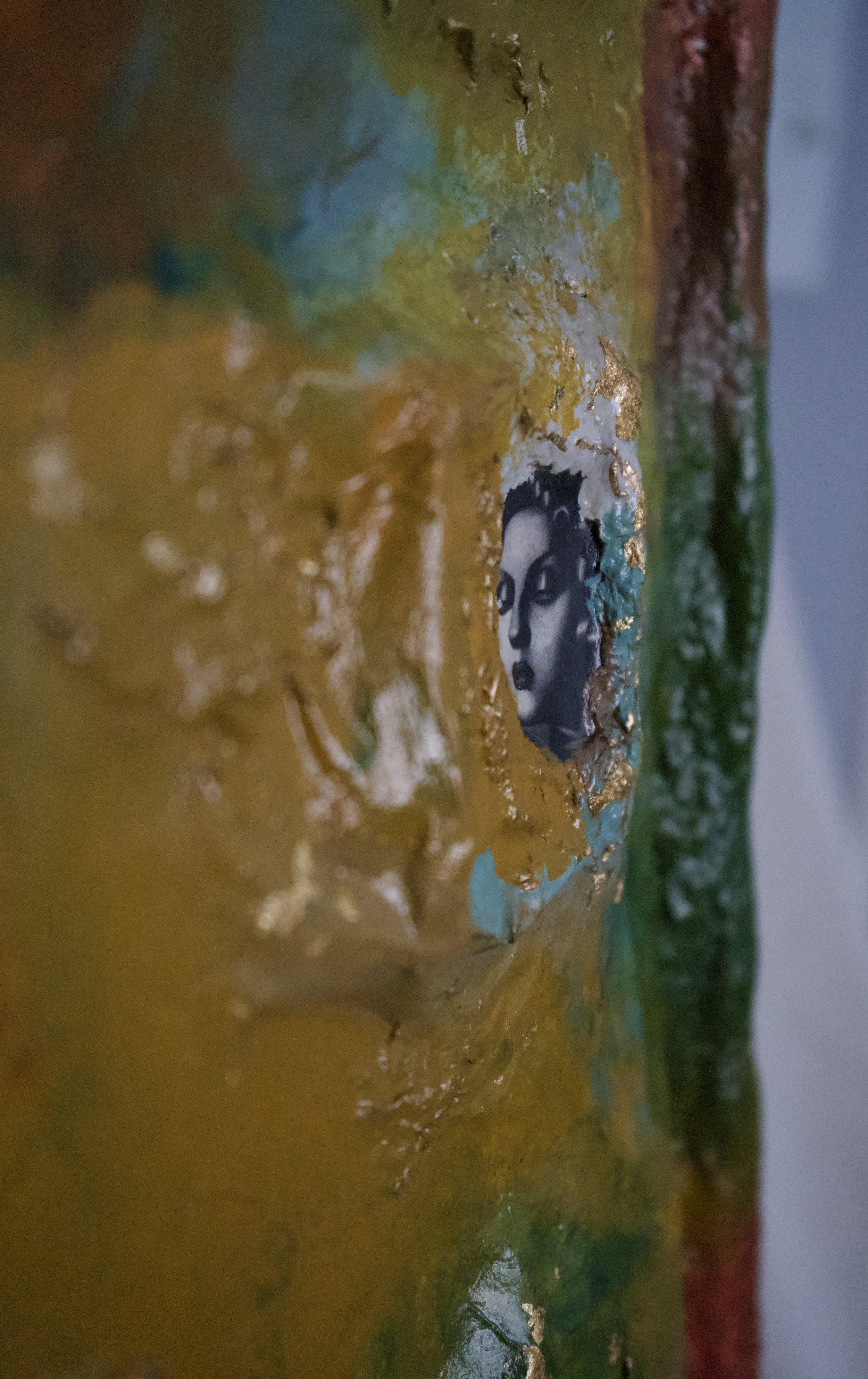 Close-up of a textured, colorful artistic surface with a small face image embedded in the design.