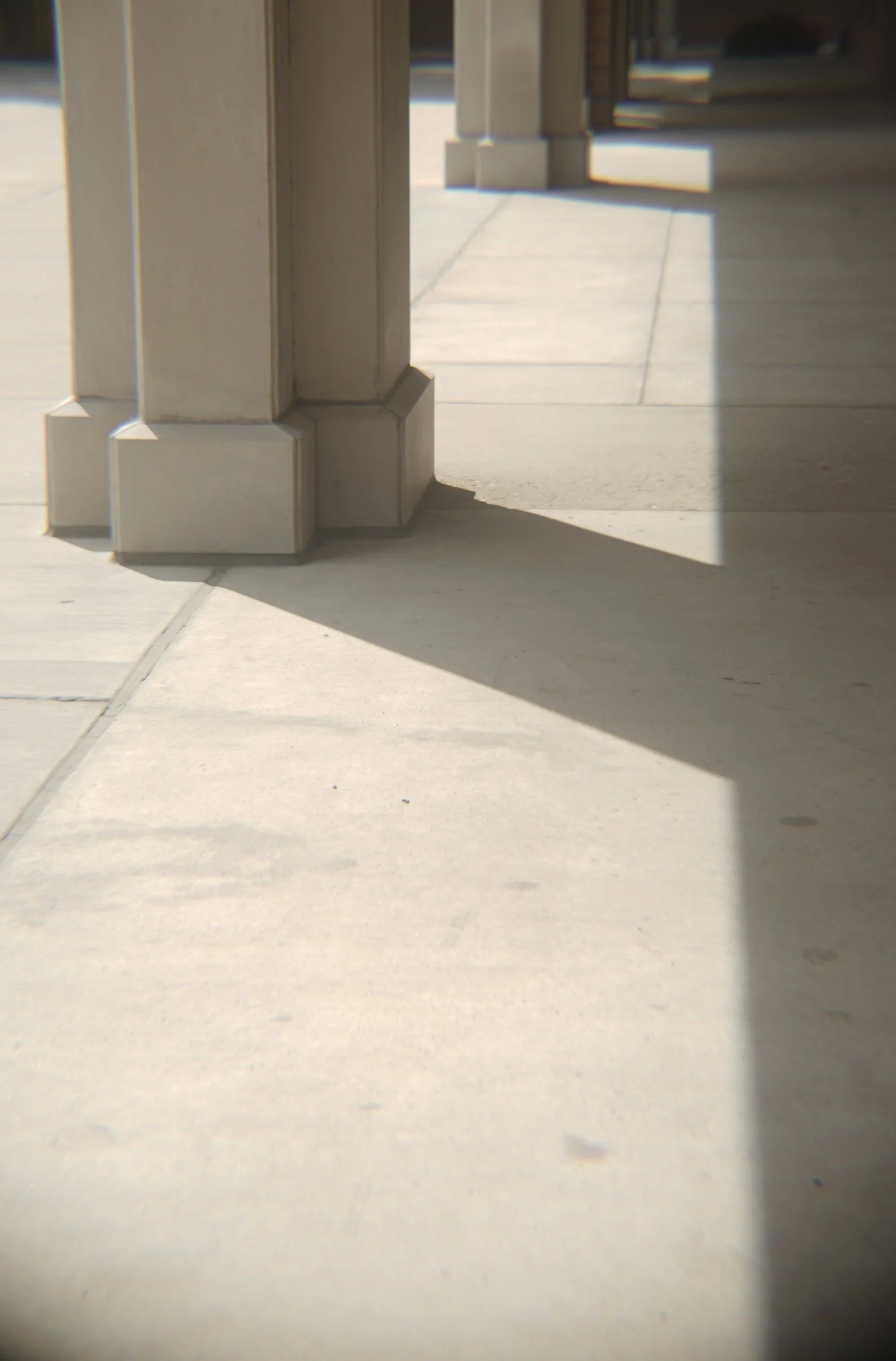 Close-up of building exterior corner with a shadow cast on the sidewalk