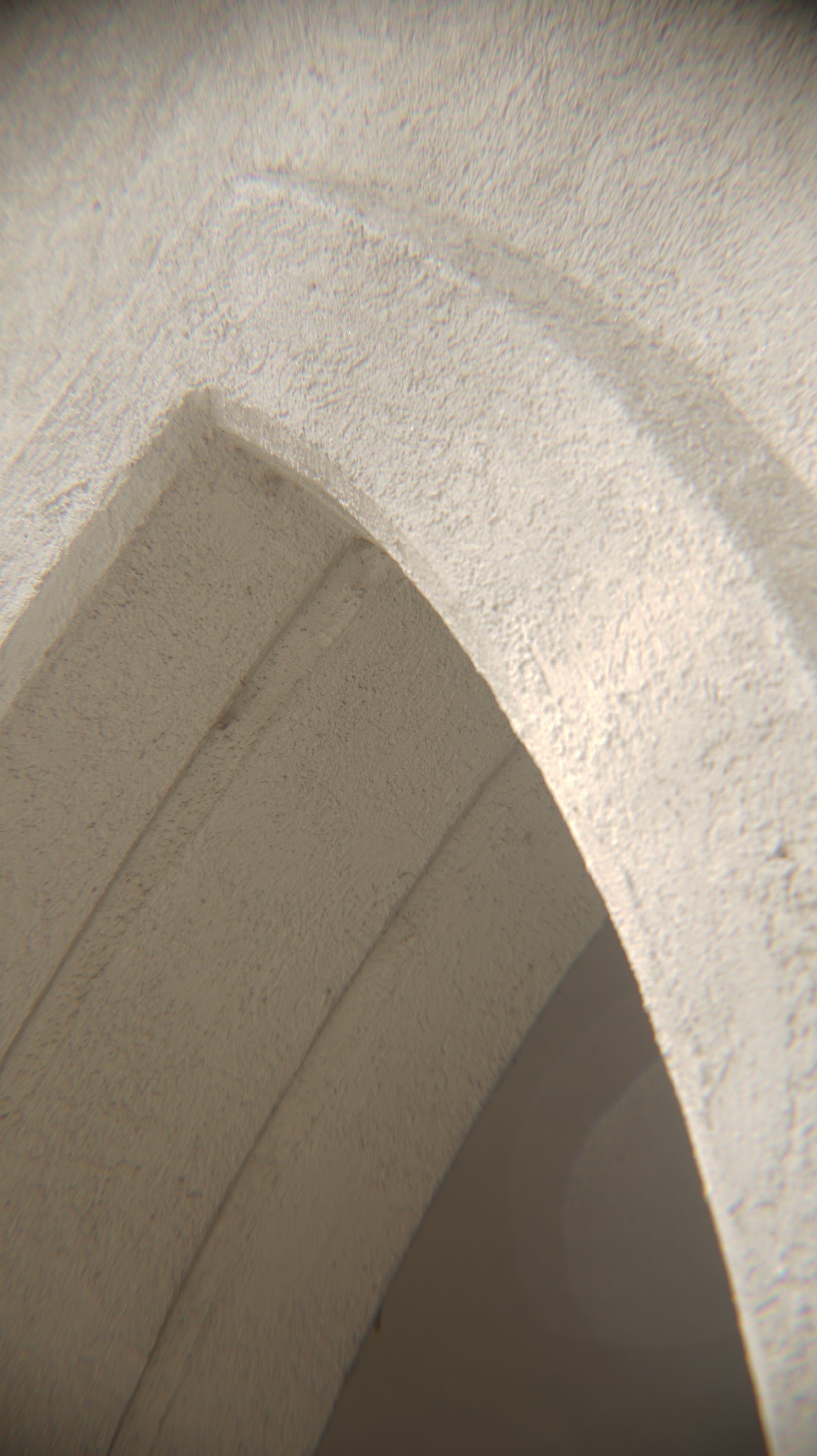 Close-up of a white textured curved ceiling or wall with visible seams.
