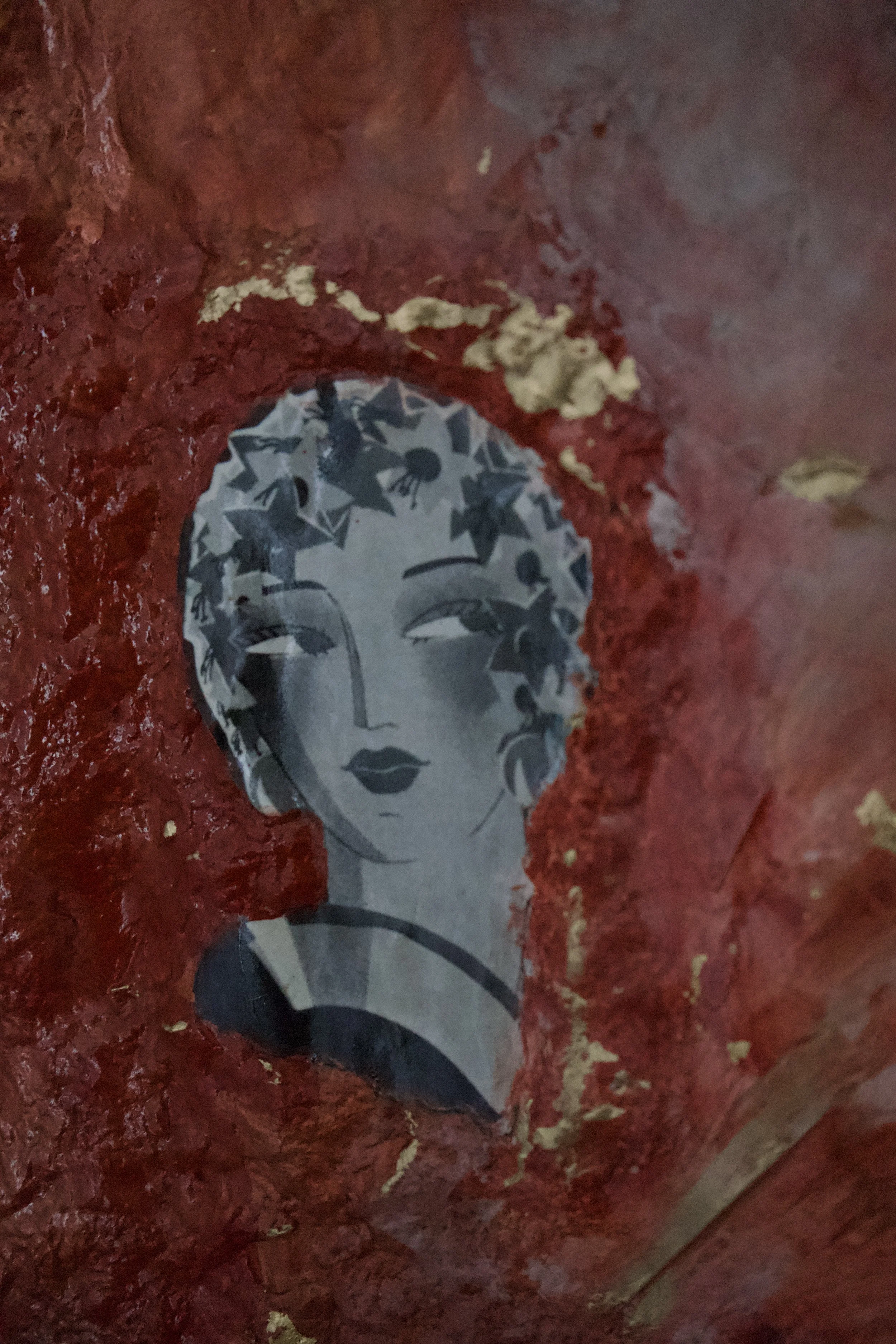 A sticker of a woman's face with closed eyes, dark lips, and hair decorated with stars and leaves, placed on a red textured surface.
