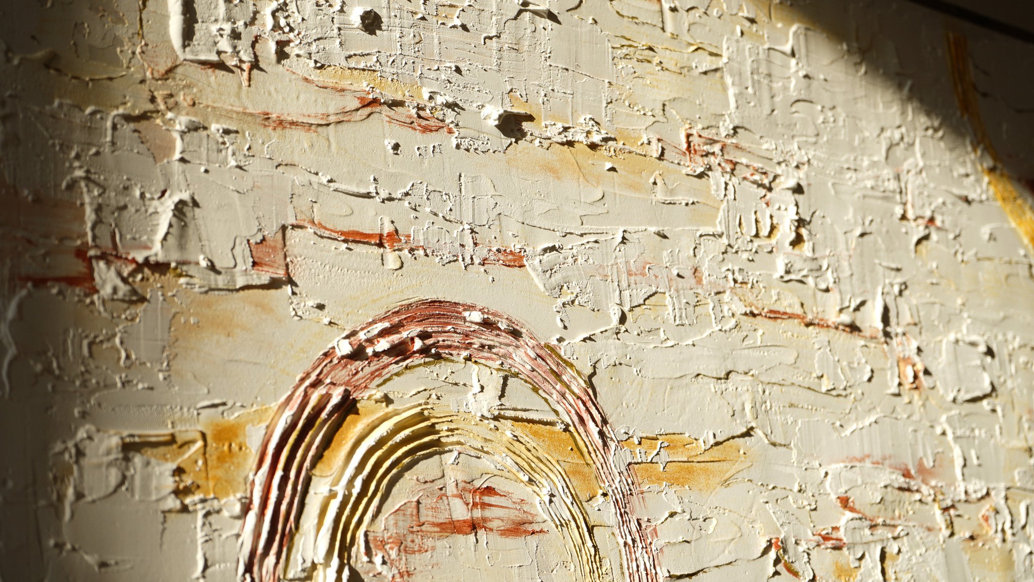 Close-up of a textured, abstract painting with thick, layered paint and a rainbow-like arch in warm colors.
