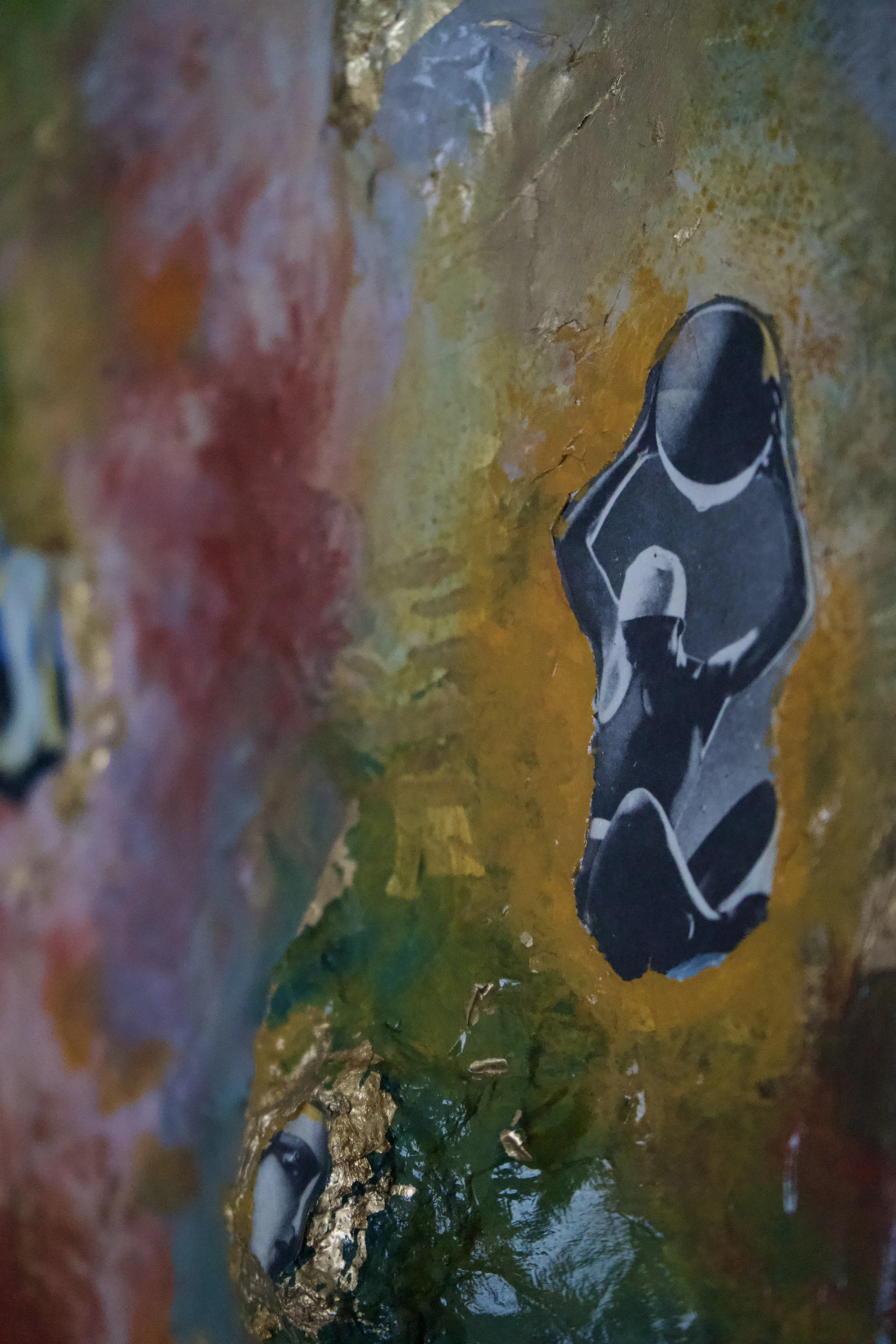 Close-up of a colorful textured surface with torn black and white photos of a woman sitting and a person in a hat.
