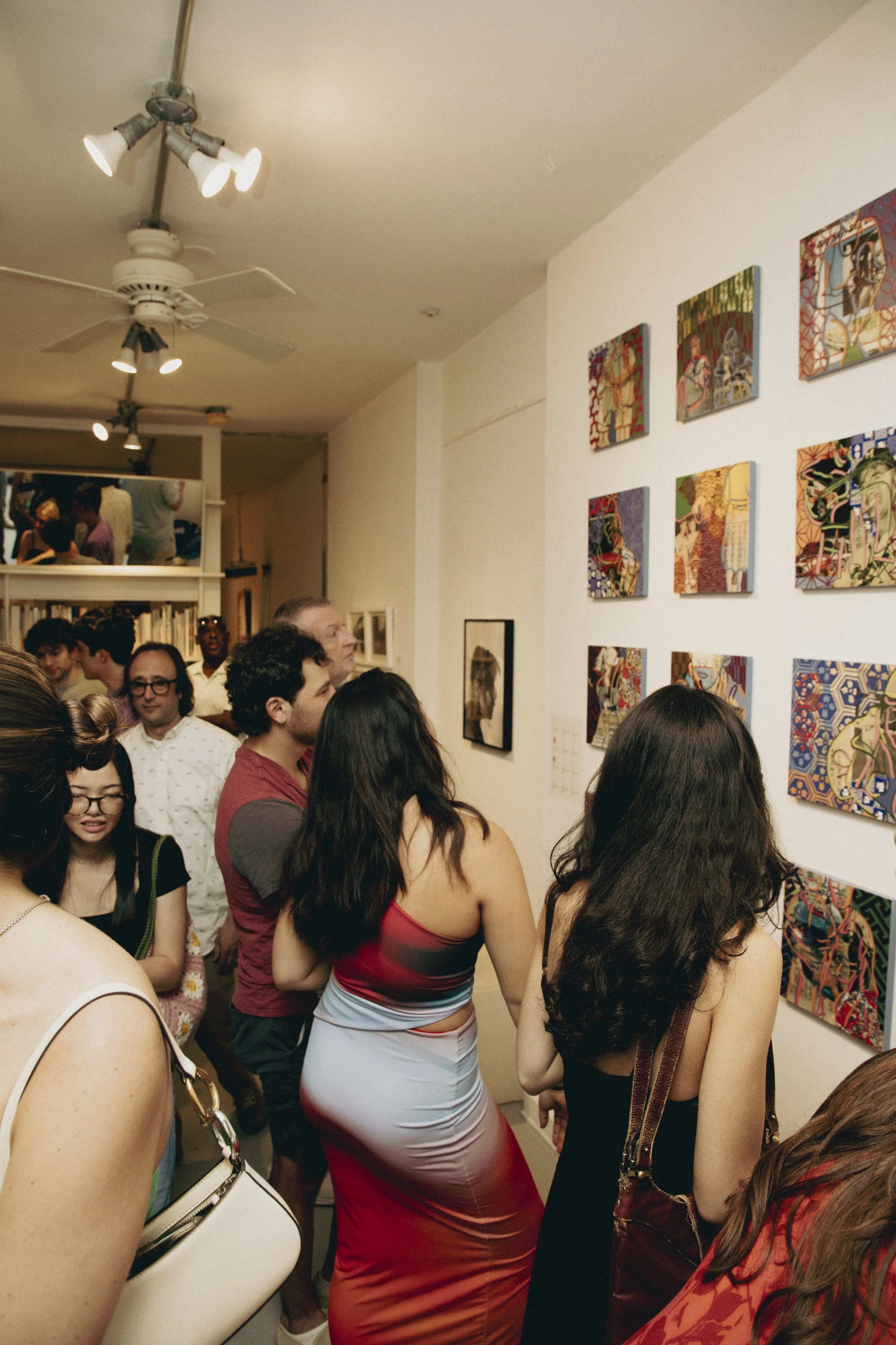 People viewing artwork on a gallery wall at an art exhibit.