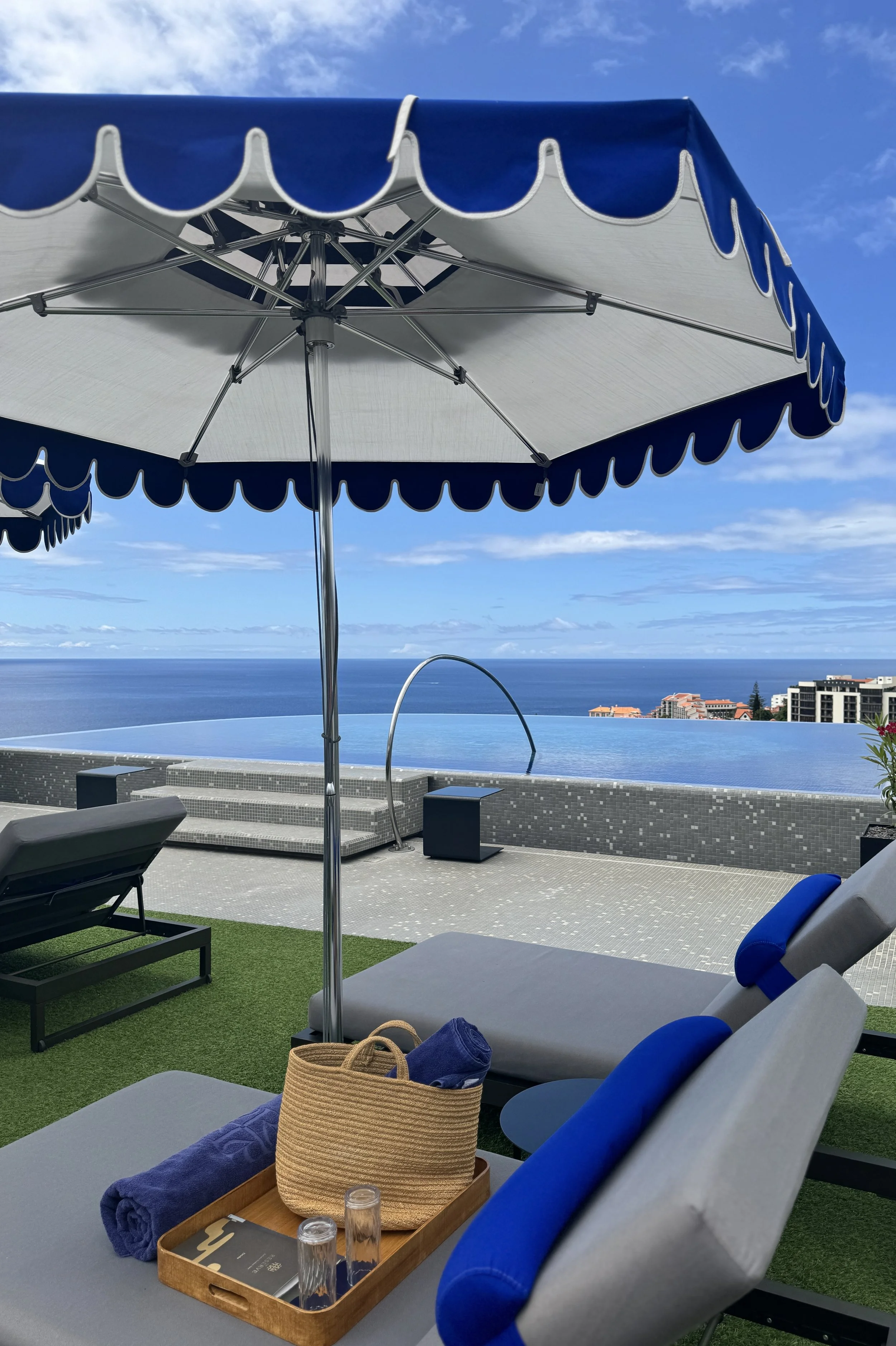 A calm gentle surf spot along Madeira’s black sand beach, where dark volcanic sand meets softly breaking Atlantic waves. The surf rolls in with an easy rhythm, creating a peaceful, understated scene against the rugged coastline of Madeira.