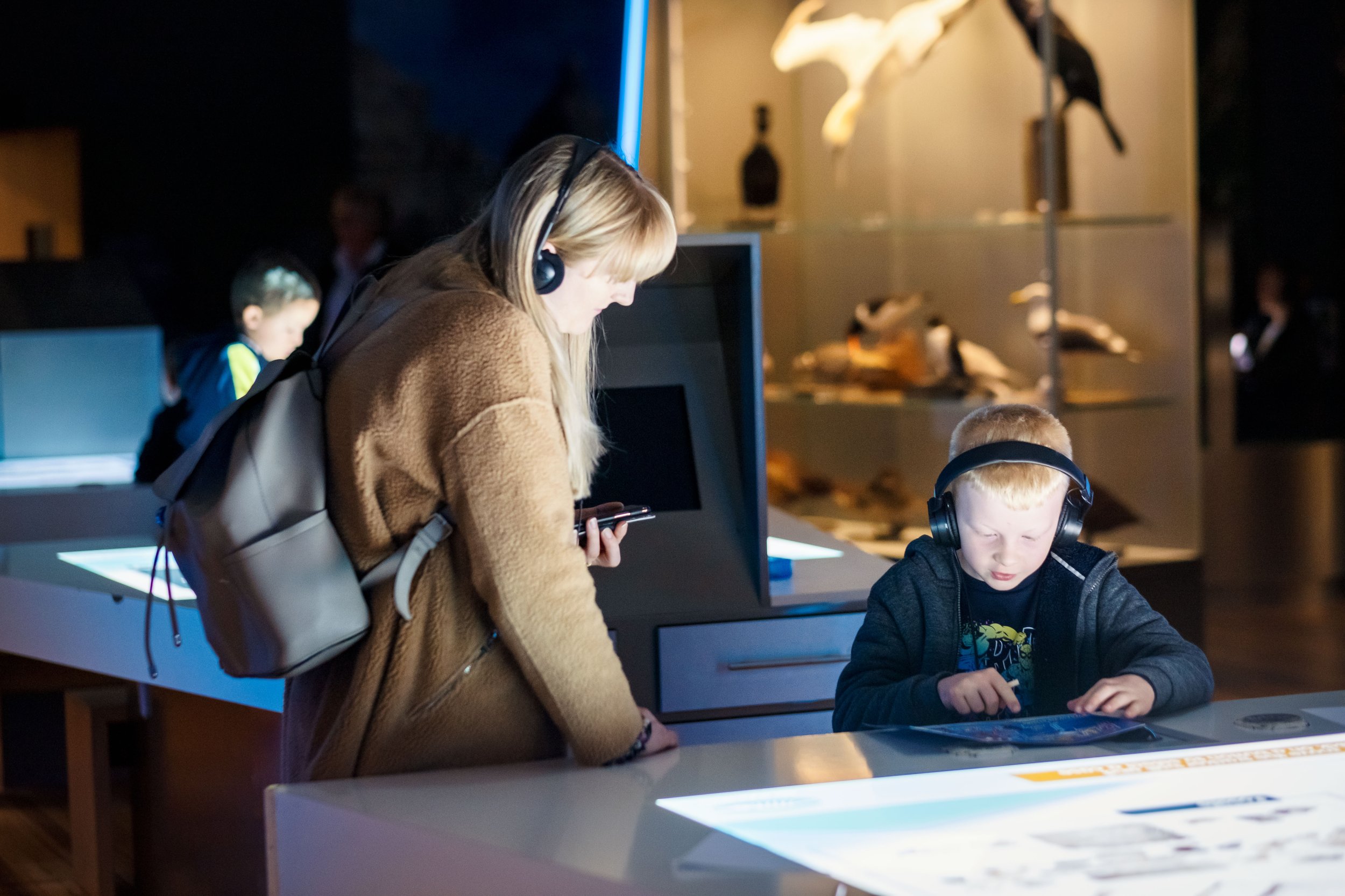 People using interactive exhibits at a museum with headphones
