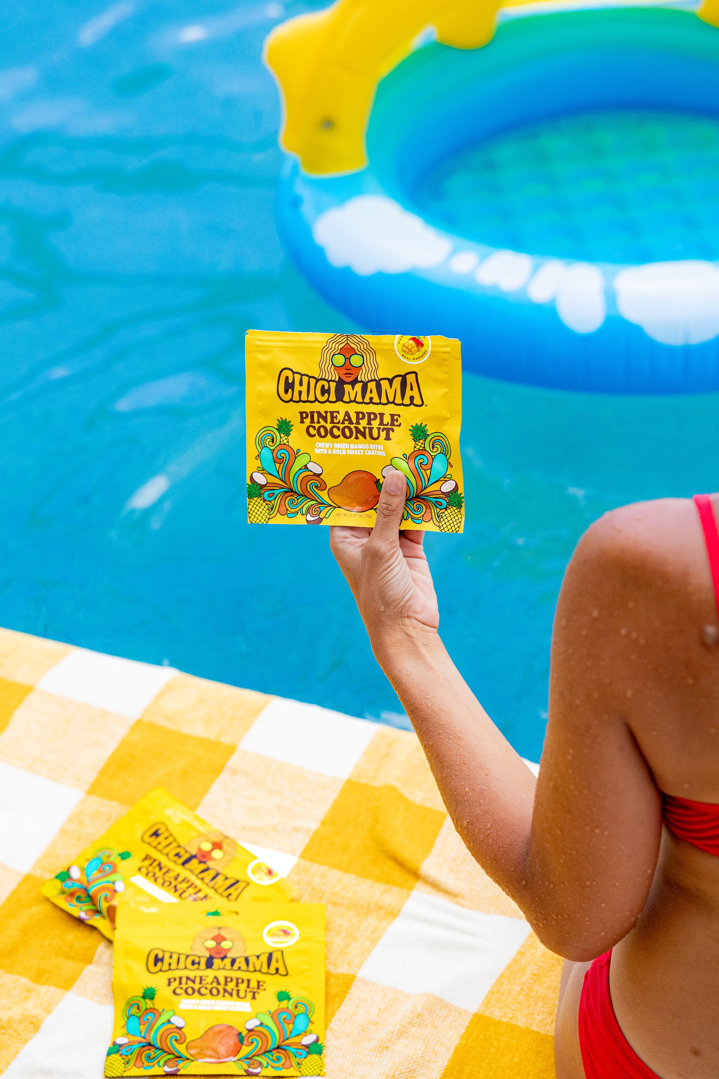 Woman in bikini relaxing poolside with Chici Mama bag, summer snack brand lifestyle content by Gabe Gonzalez