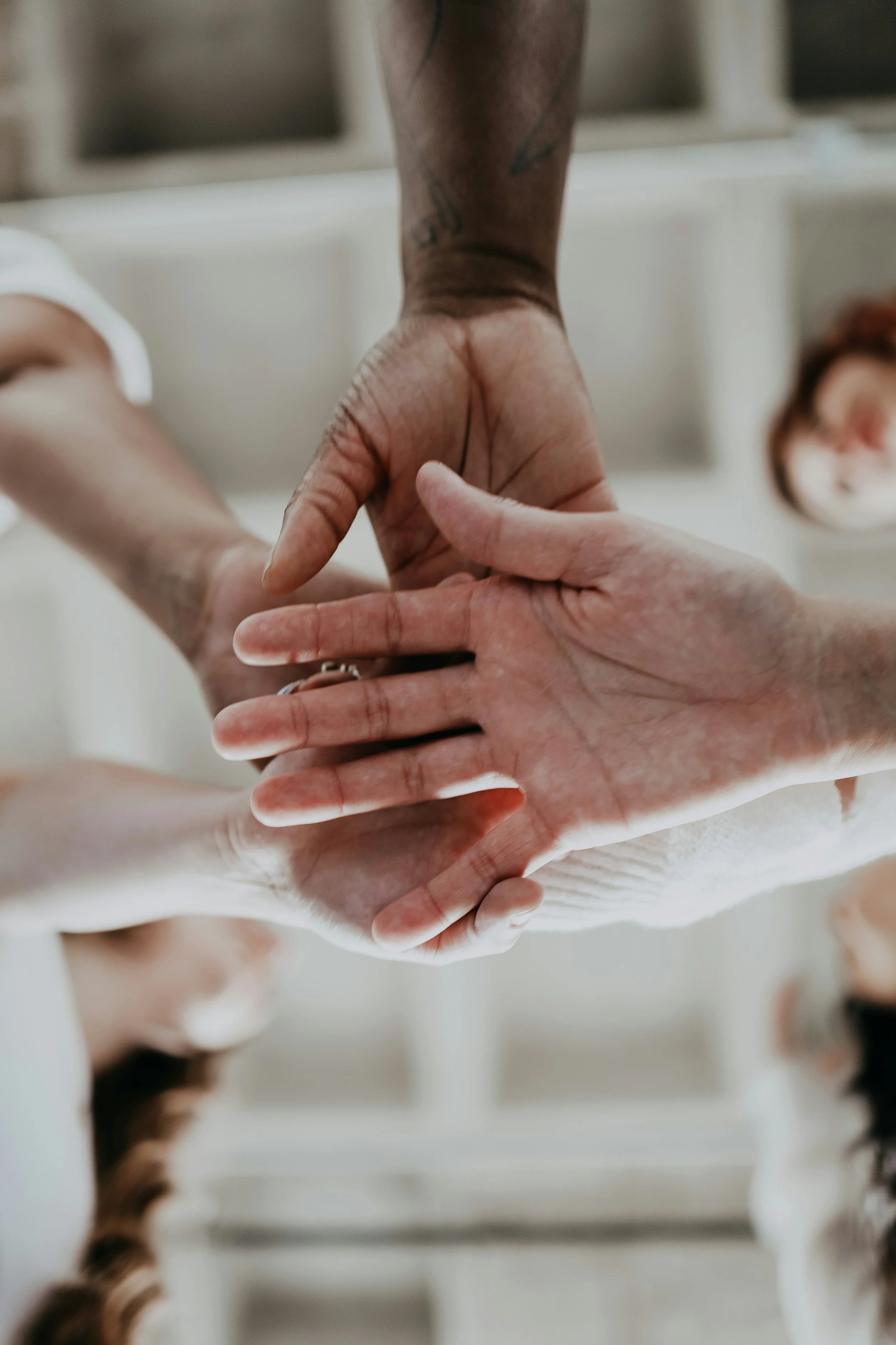 Multiple hands stacked together in a gesture of unity or teamwork.
