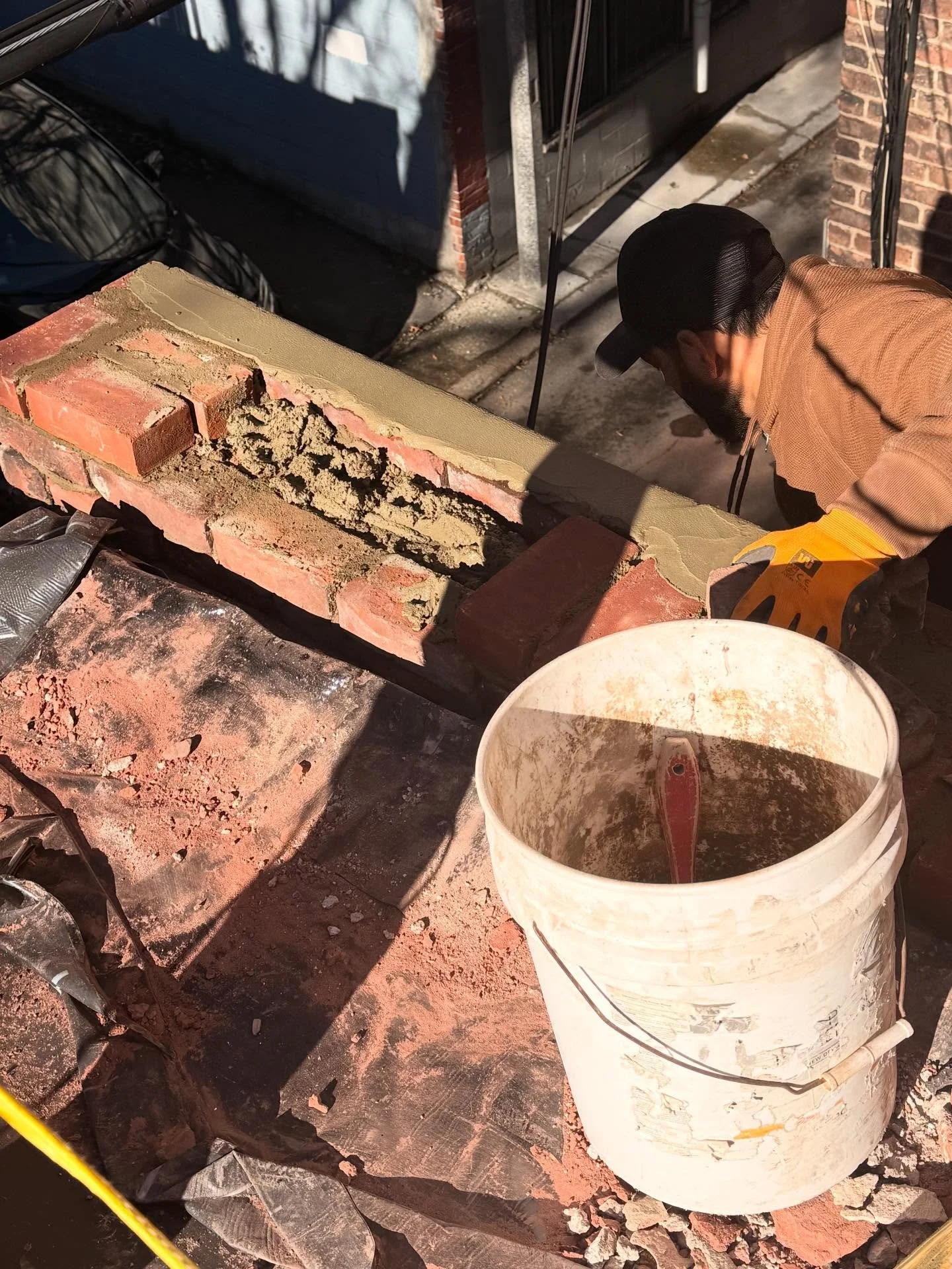 The masonry team repaired and replaced the bricks on the roof to restore the structural integrity of the building. They used mudding to fill gaps and secure the new bricks, ensuring a stable and long-lasting repair.