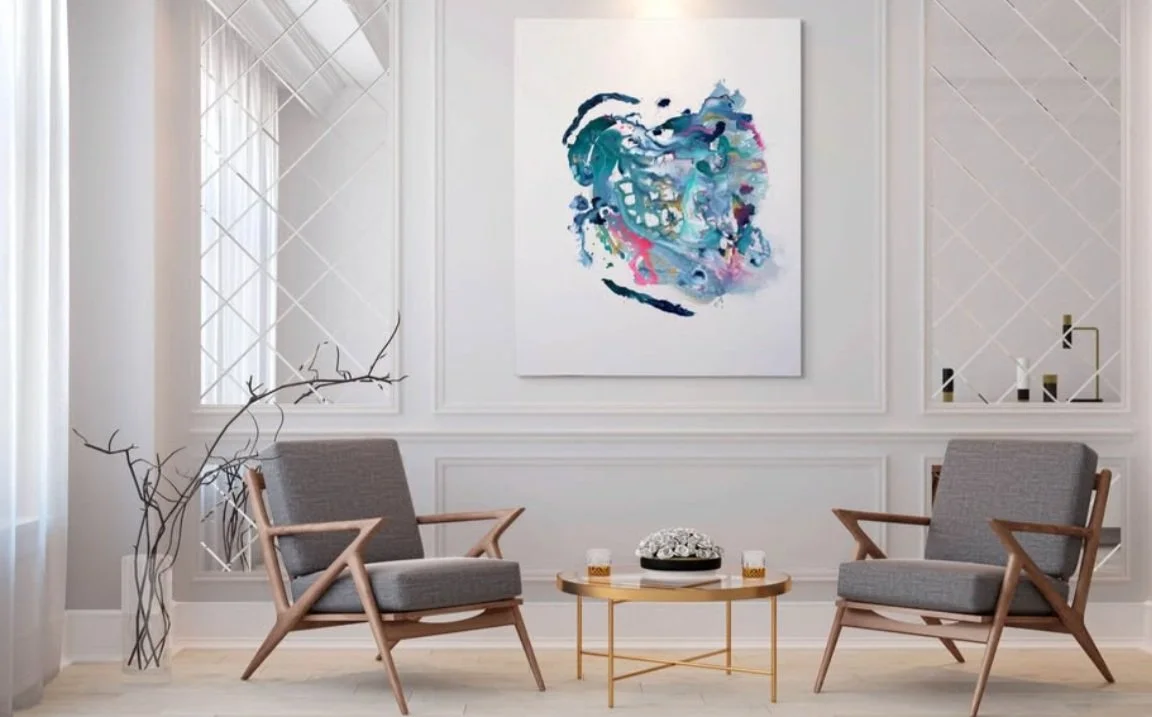 Minimalist living room with two gray armchairs, a round coffee table, abstract wall art, and light-colored walls.
