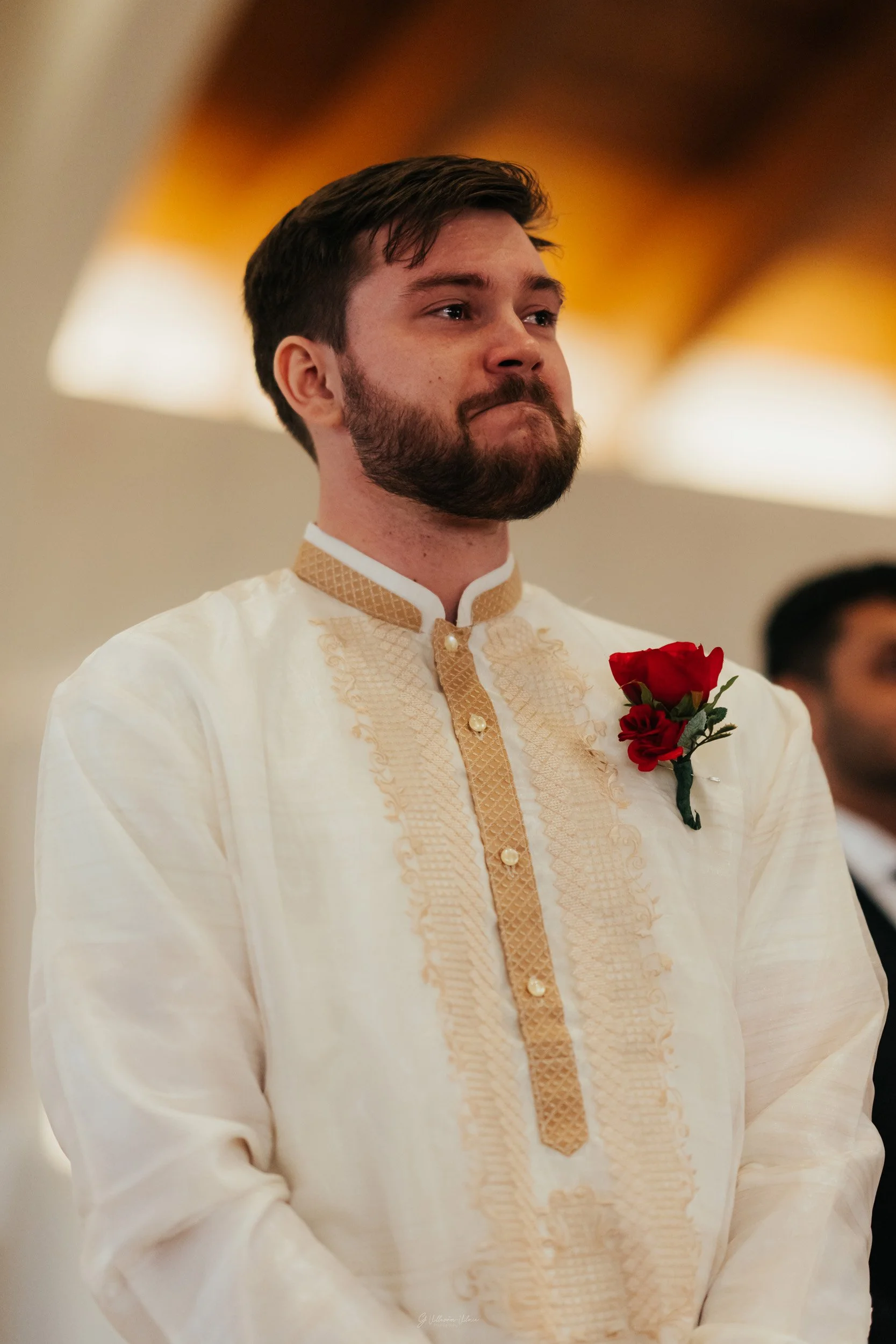 Man wearing traditional Filipino Barong Tagalog with a red rose boutonniere during a formal event.