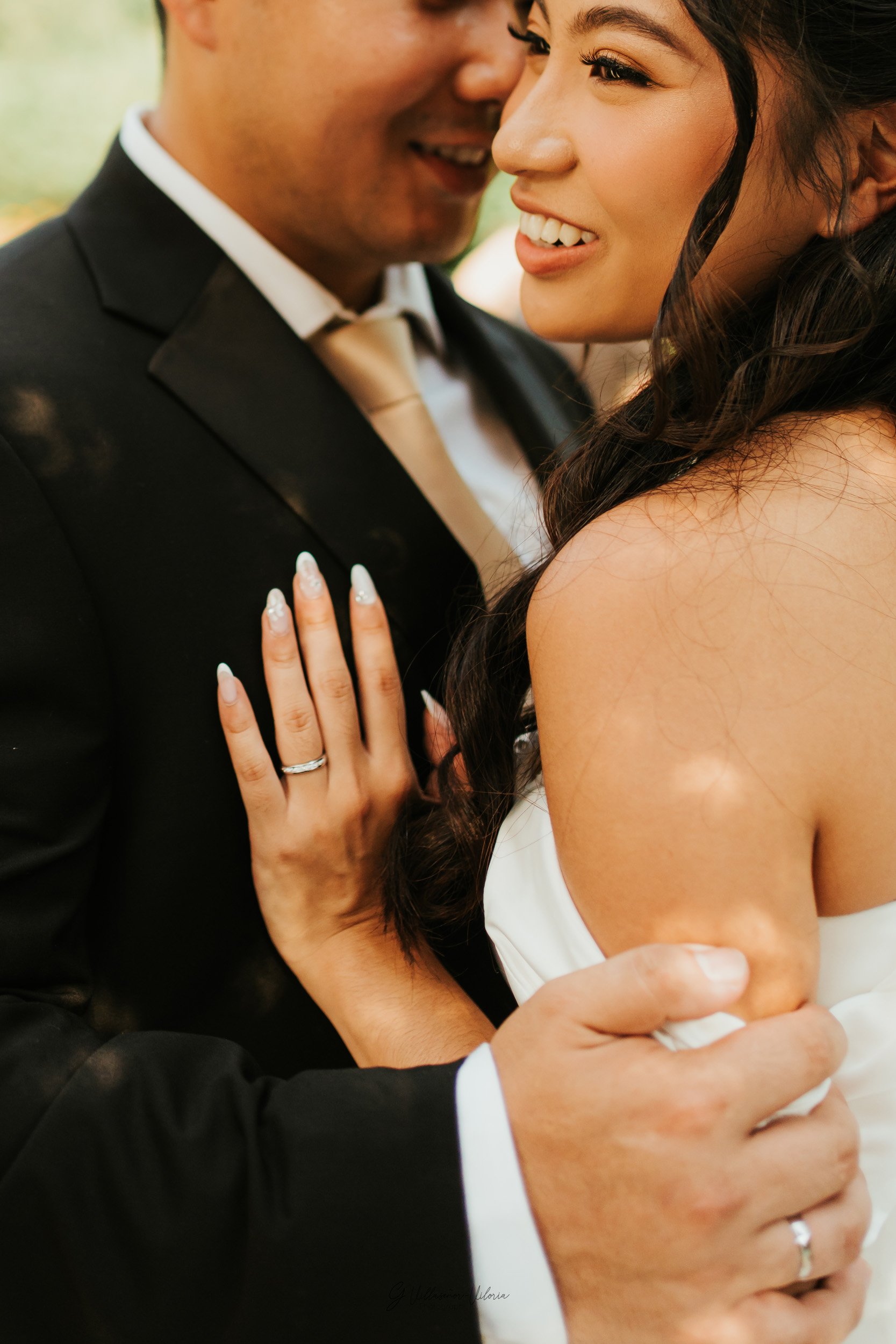 A close-up of a bride and groom embracing during a wedding, smiling and showing love.