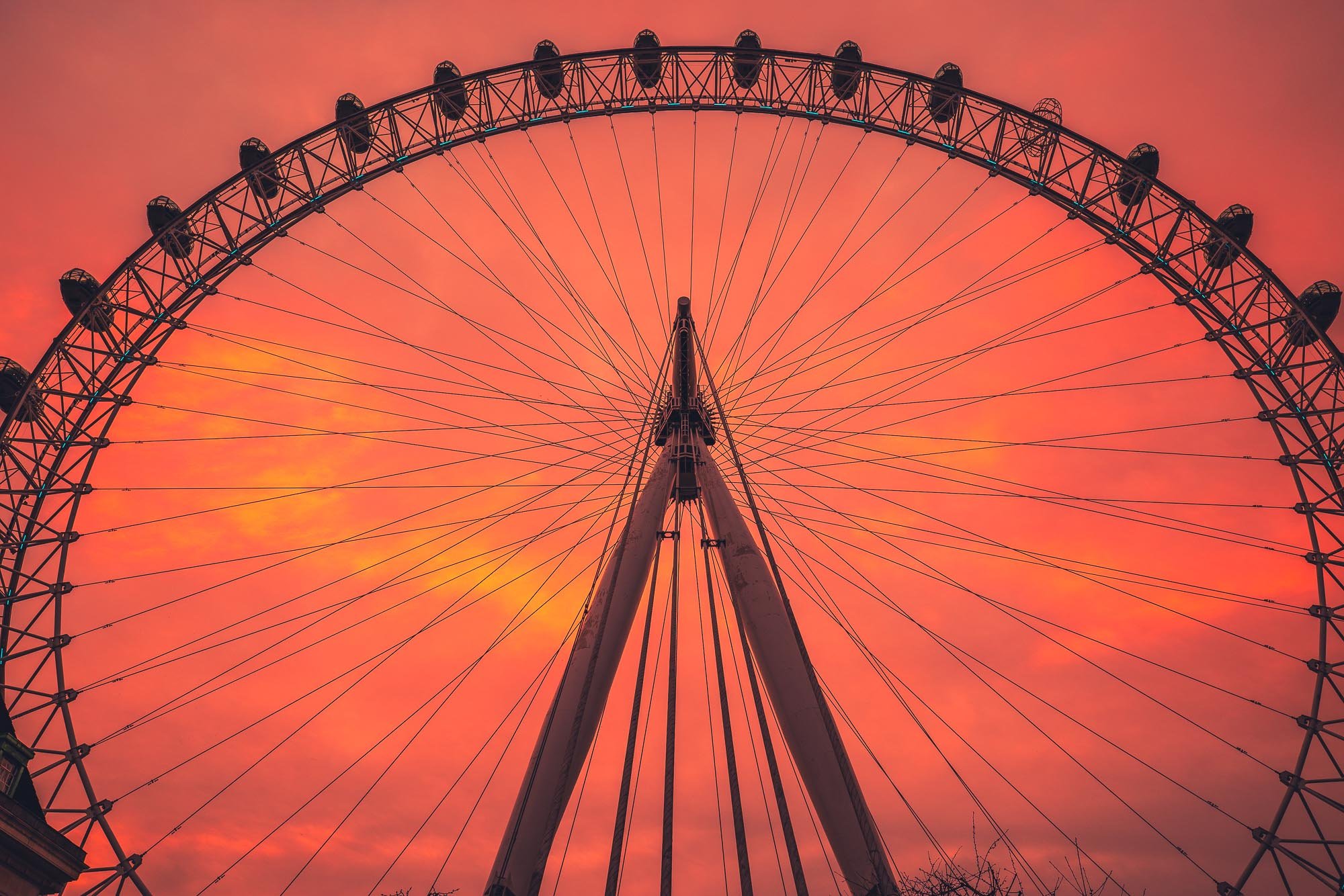 View of a giant Ferris wheel during a vibrant orange and pink sunset sky.