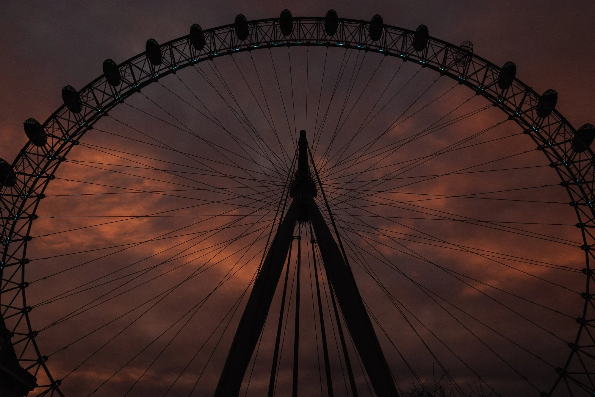 A large Ferris wheel silhouette against a dusky orange and purple sky at sunset.