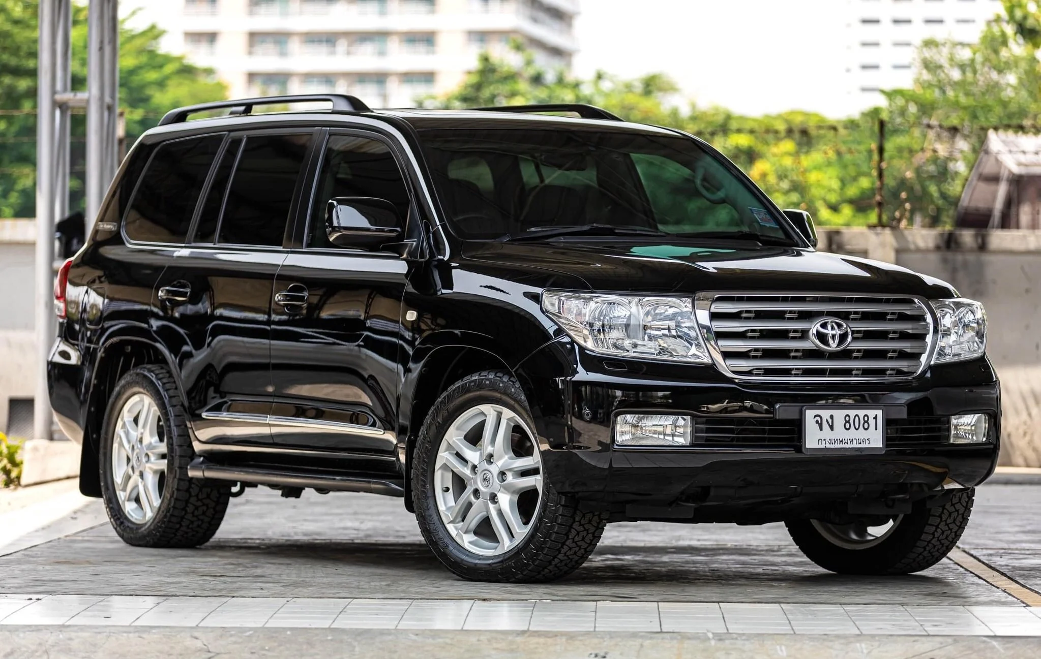 A black Toyota SUV parked on a paved surface in an outdoor area with trees and a building in the background.