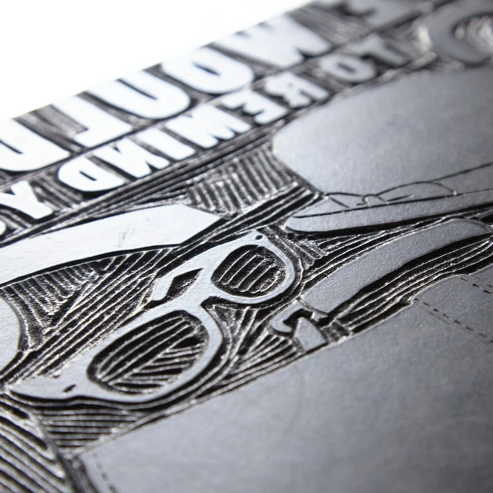 Close-up of engraved design on a surface, featuring glasses and text in bold letters.
