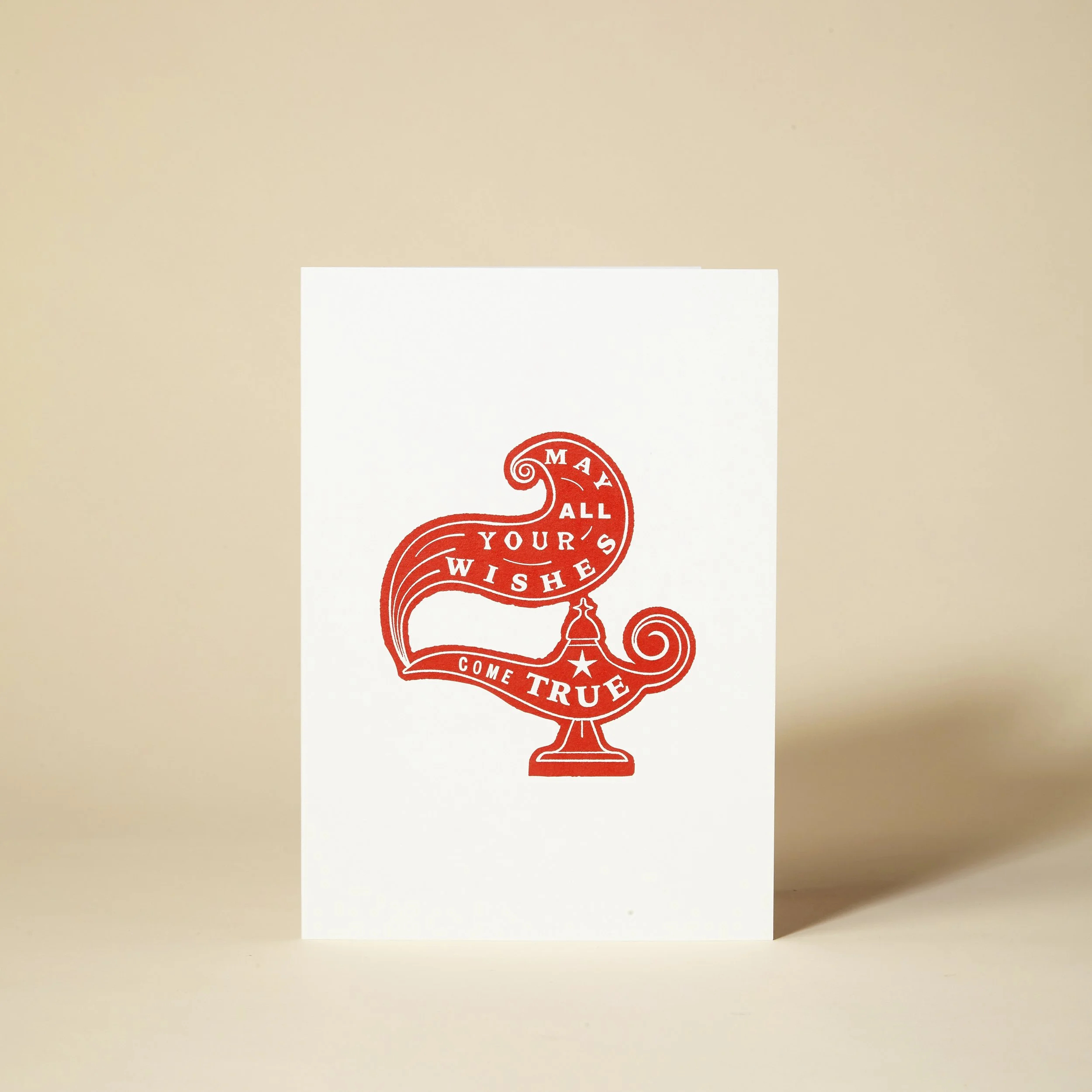 Greeting card with red illustration of a genie lamp and the text "May all your wishes come true."