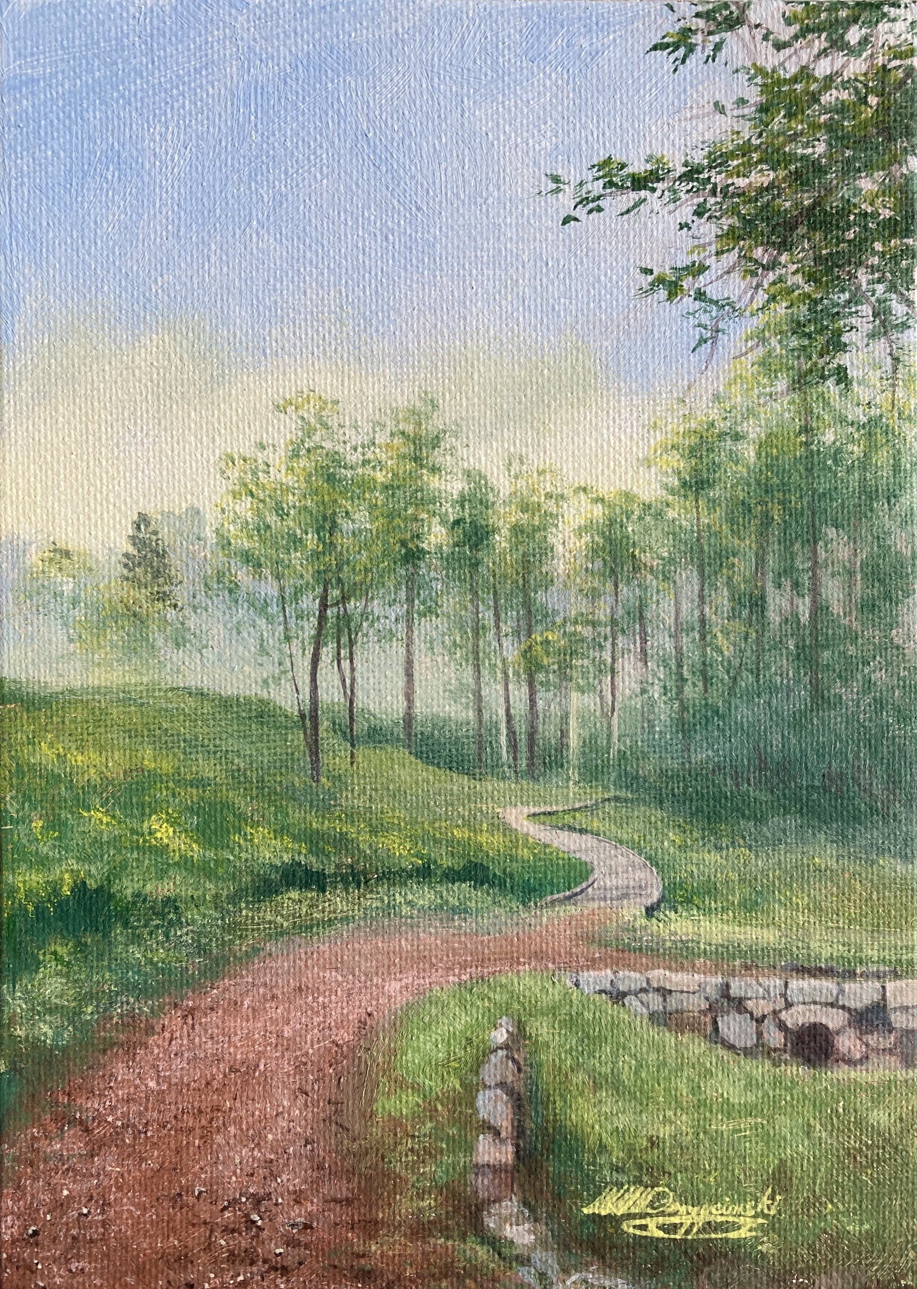 dirt road forks to wind past grassy hills trees in distance