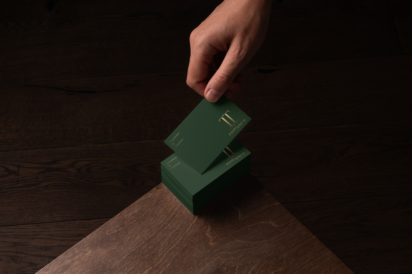 Pontto Fiscal business card design featuring a metallic gold TT monogram on premium dark green stationery, presented on a wooden surface, as part of the brand identity created by Out of Form Studio.