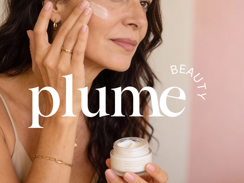Plume Beauty brand identity featuring an elegant white serif wordmark and curved BEAUTY typography over an editorial photograph of a woman applying face cream while holding a skincare jar, against a soft pink background.