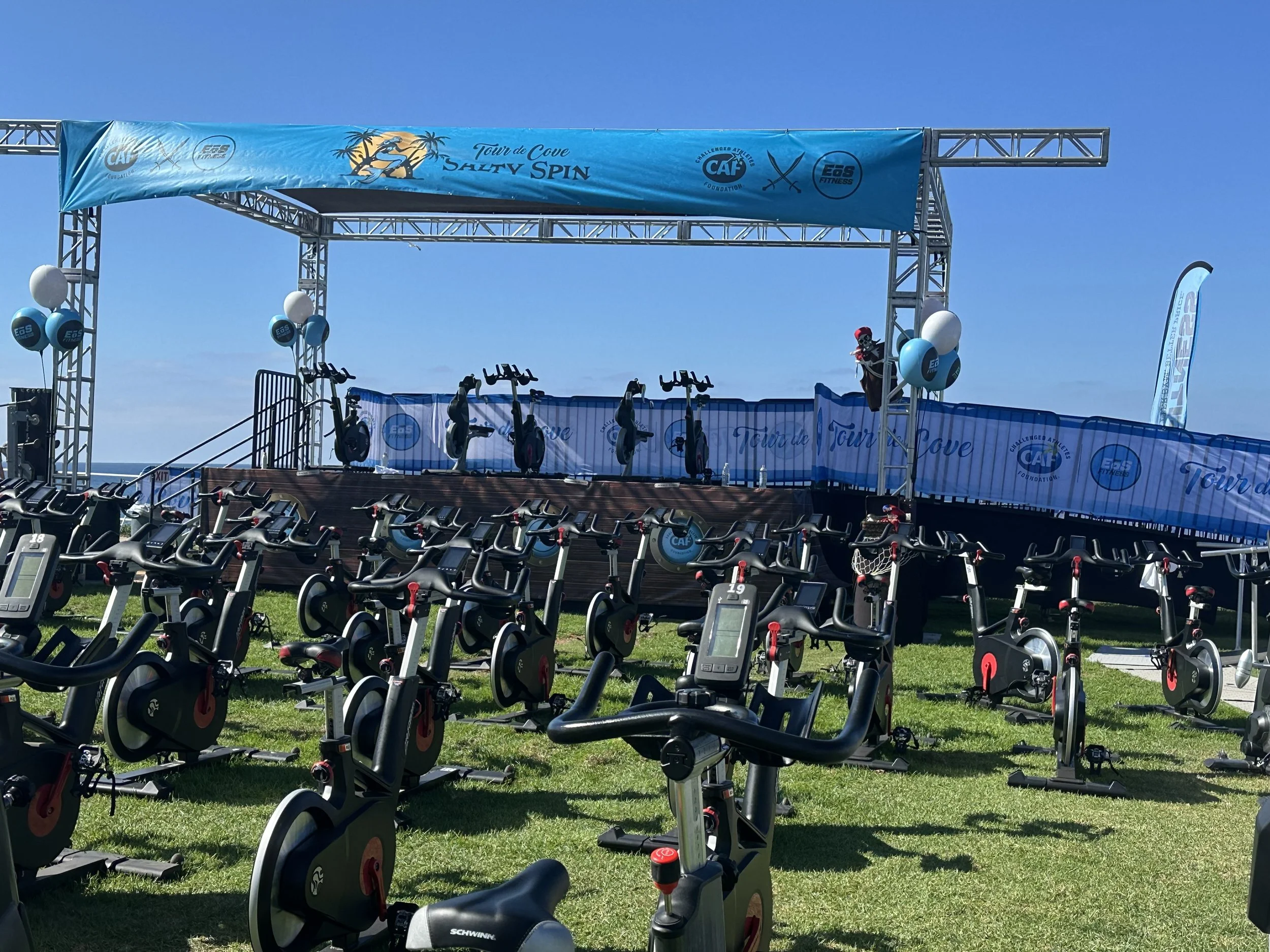 Outdoor aluminum truss and stage setup for a triathlon event featuring spin bikes and sponsor branding, designed for coastal With a full ada ramp to this stage and city park venues in Los Angeles, San Diego, and Las Vegas.