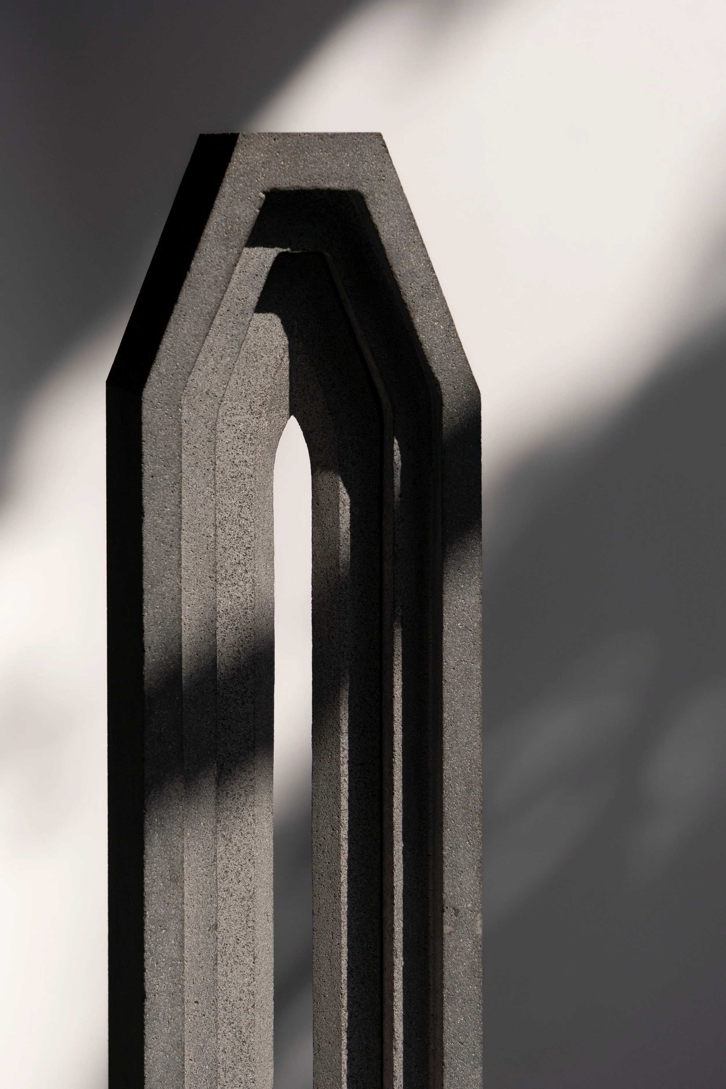 Estructura triangular de metal gris con sombra en fondo blanco y gris.