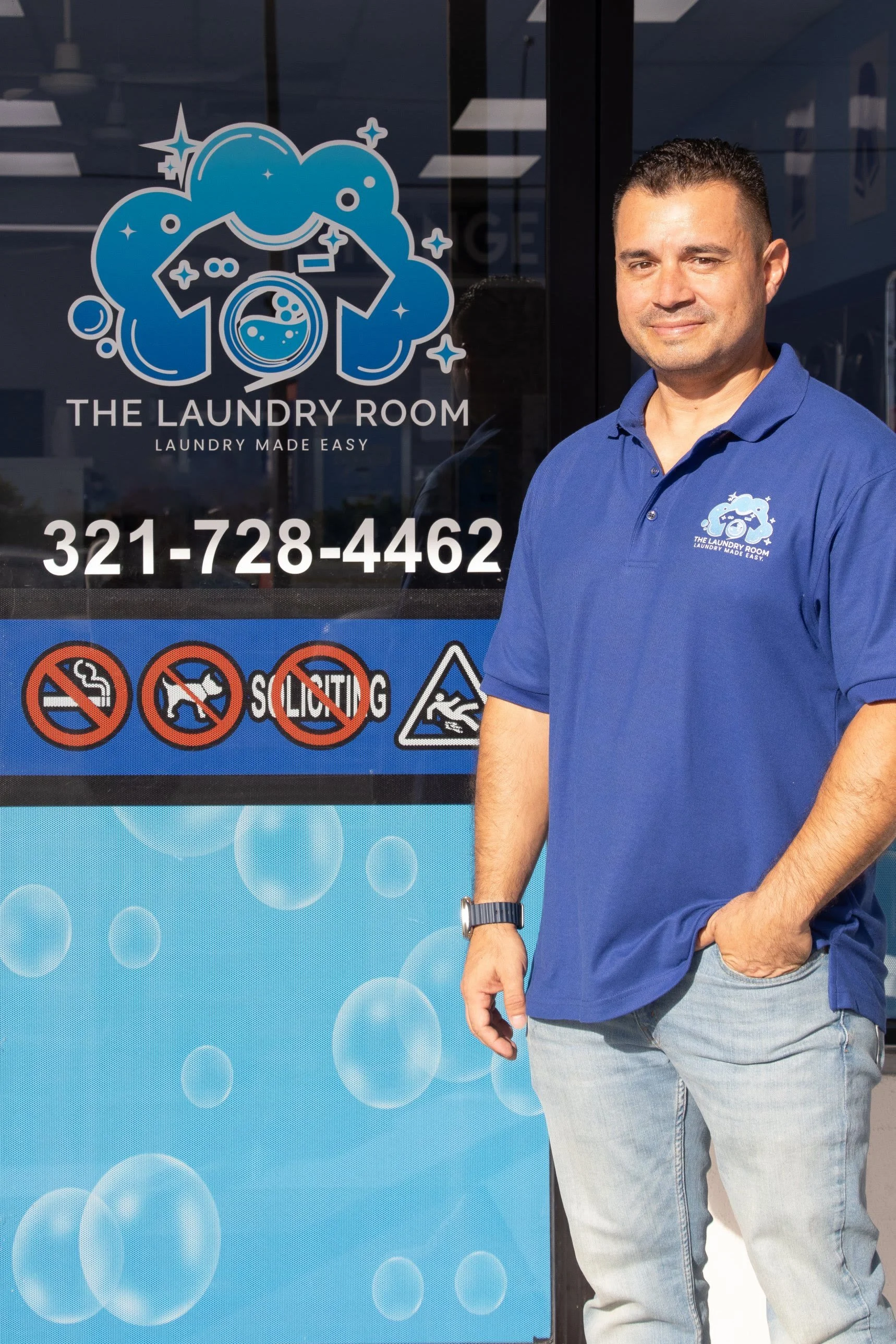 Leonard of The Laundry Room smiling beside the shop window with the Laundry Room logo