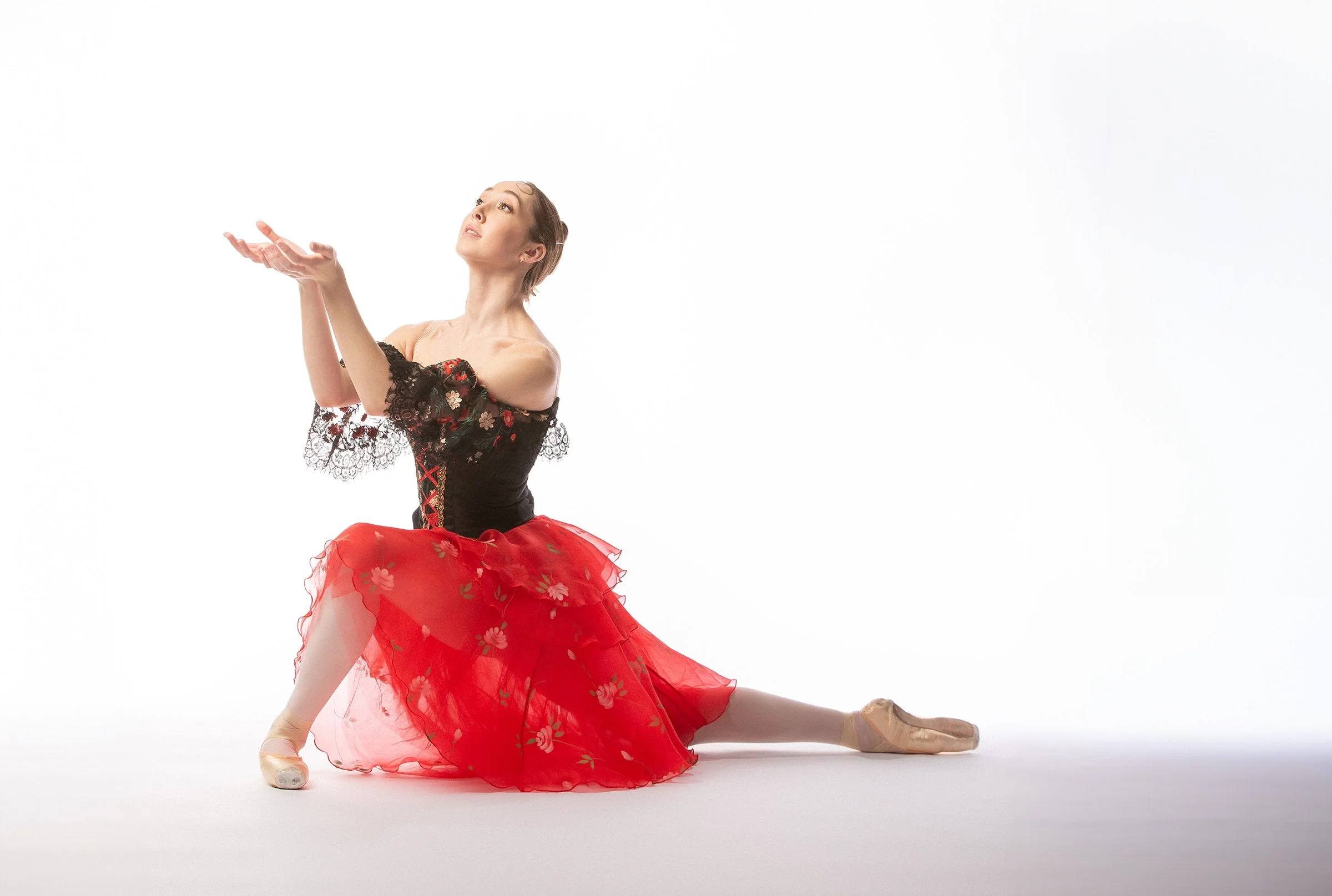 a ballet dancer kneeling in a red and black costume