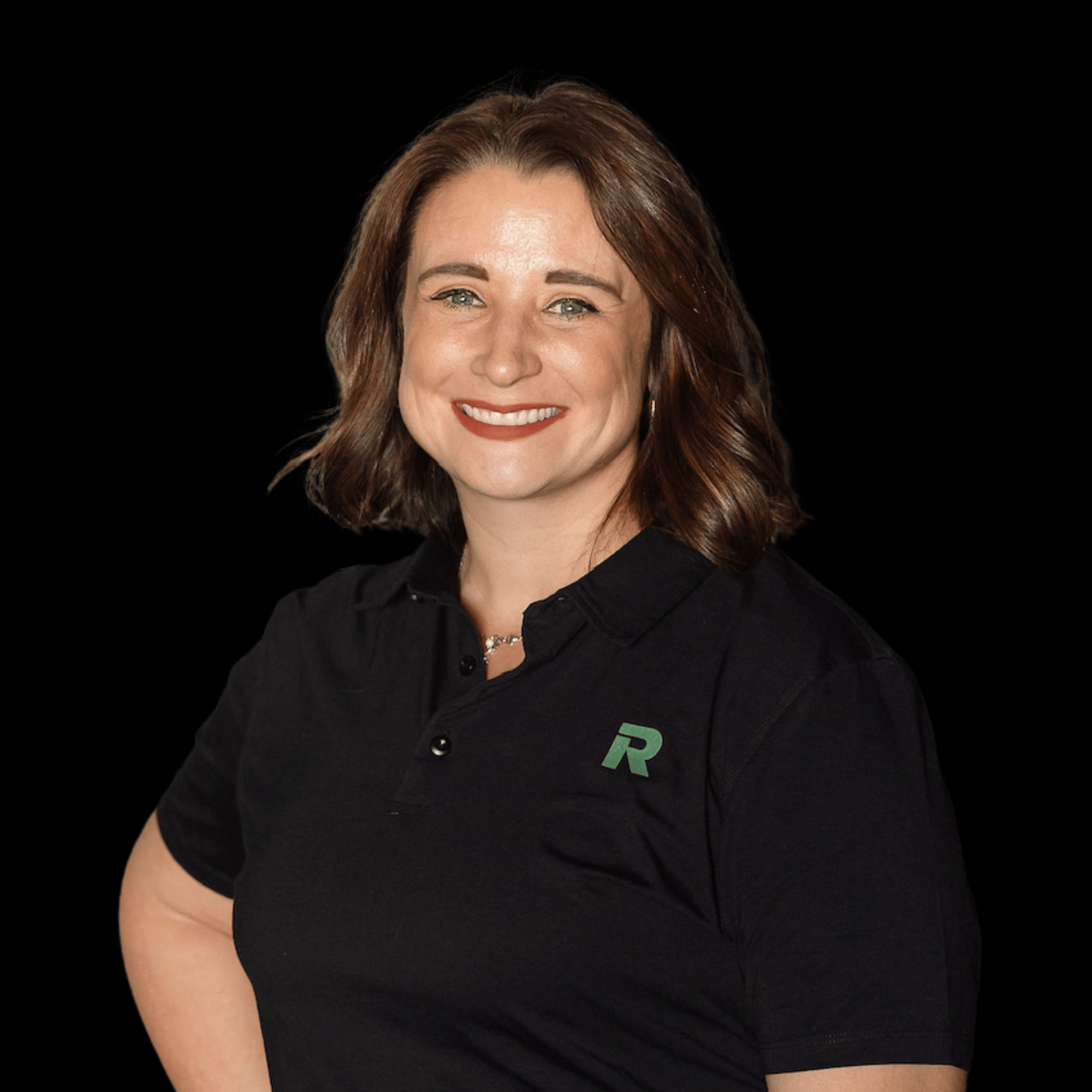 A woman with shoulder-length brown hair, smiling, wearing a black collared shirt with a green and gray 'R' logo on the chest, against a black background.