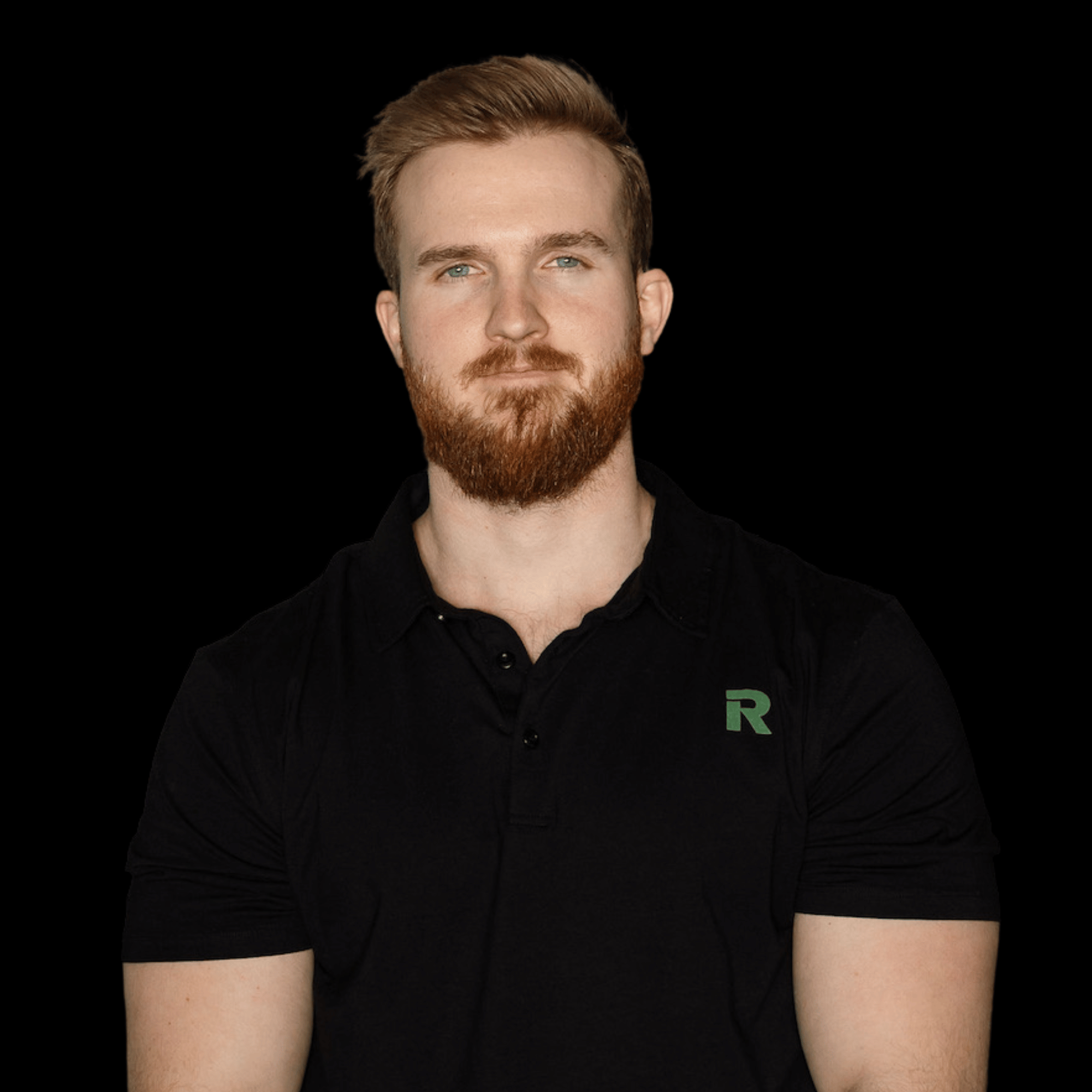 Portrait of a young man with red hair and beard, wearing a black polo shirt with a green 'R' logo, against a black background.