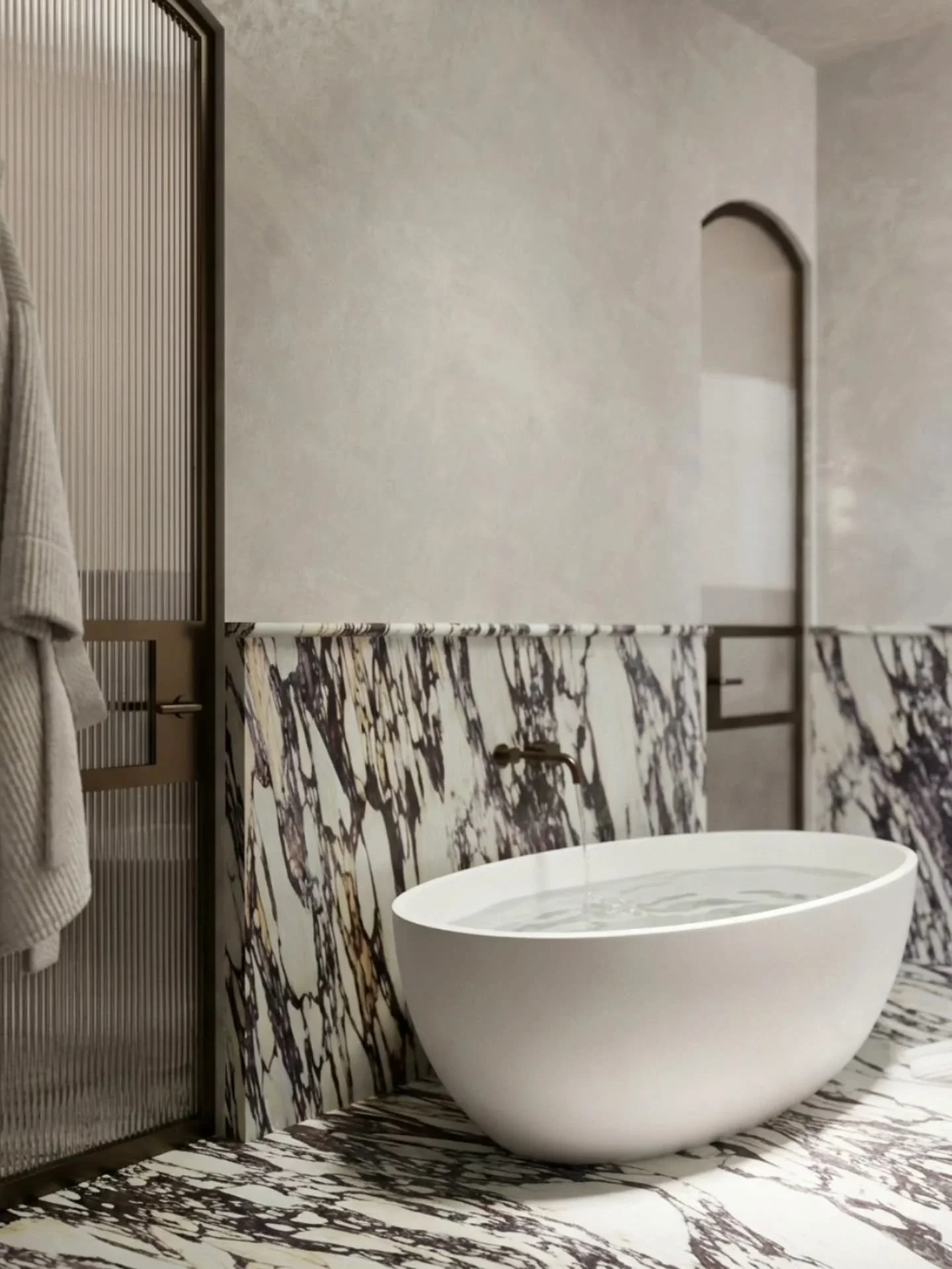 Freestanding white bathtub beside marble wall and floor finishes in a Middle Park bathroom.
