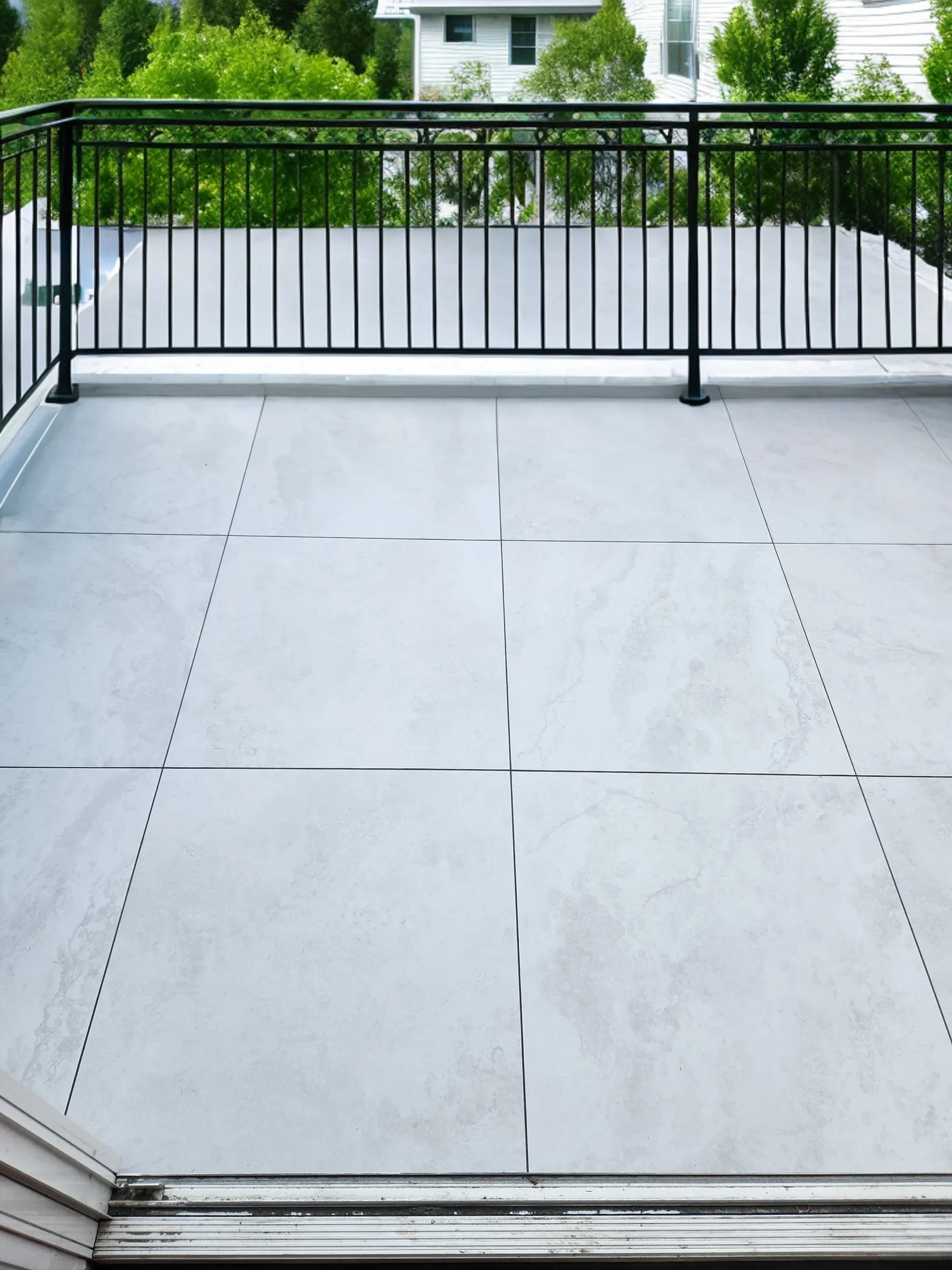 Newly tiled balcony with large-format tiles and a black metal railing