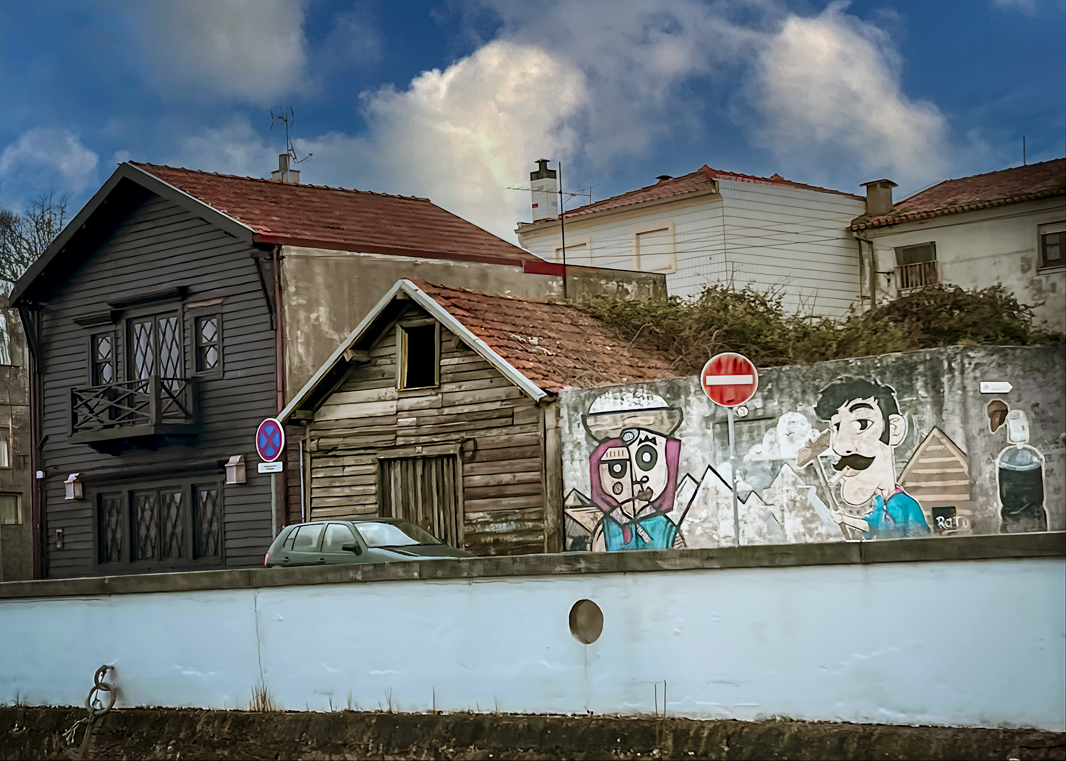 The artwork is a mural painted on a concrete wall in Aveiro Portugal.
 It features two stylized human faces with distinct cartoonish and exaggerated features