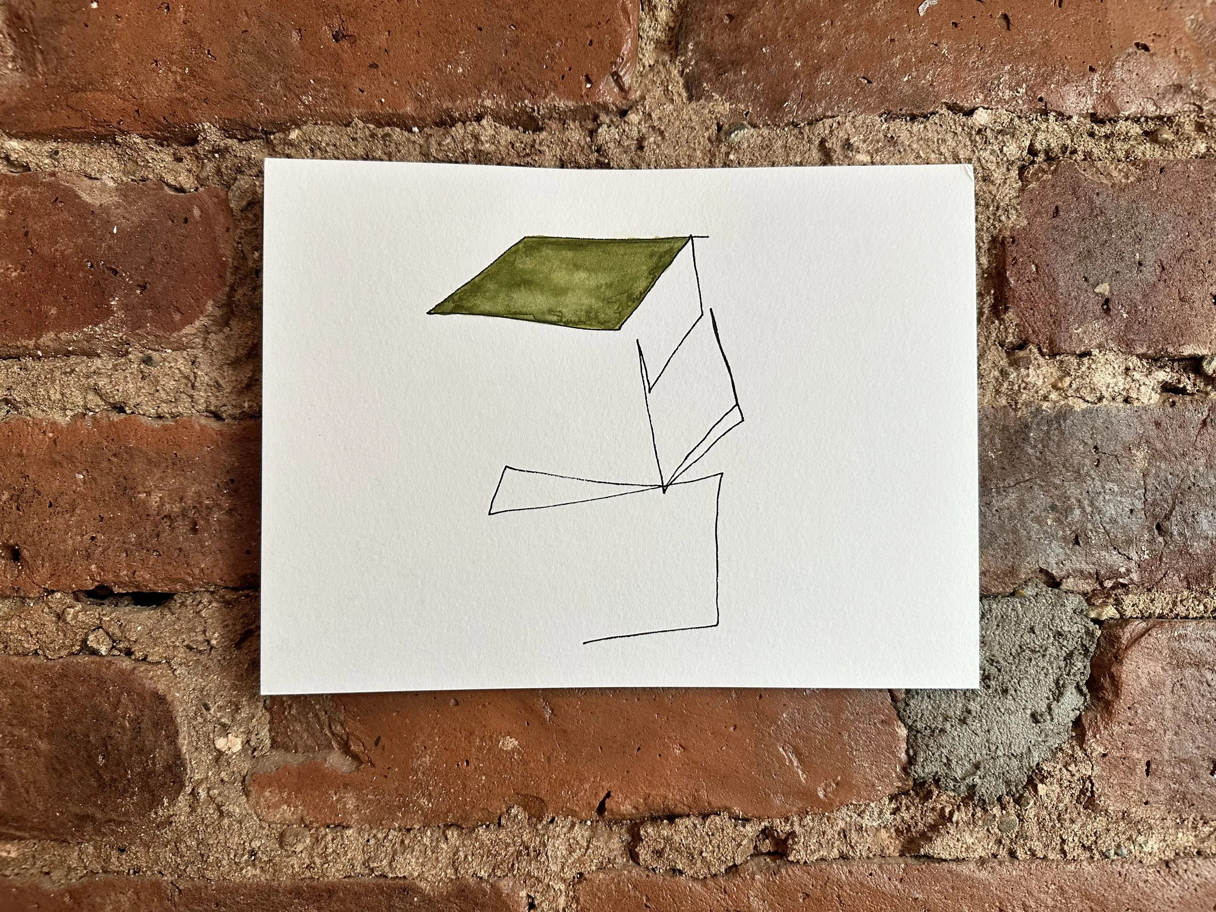 A white piece of paper with a minimalist drawing of a 3D geometric shape, with one face colored green, set against a brick wall background.