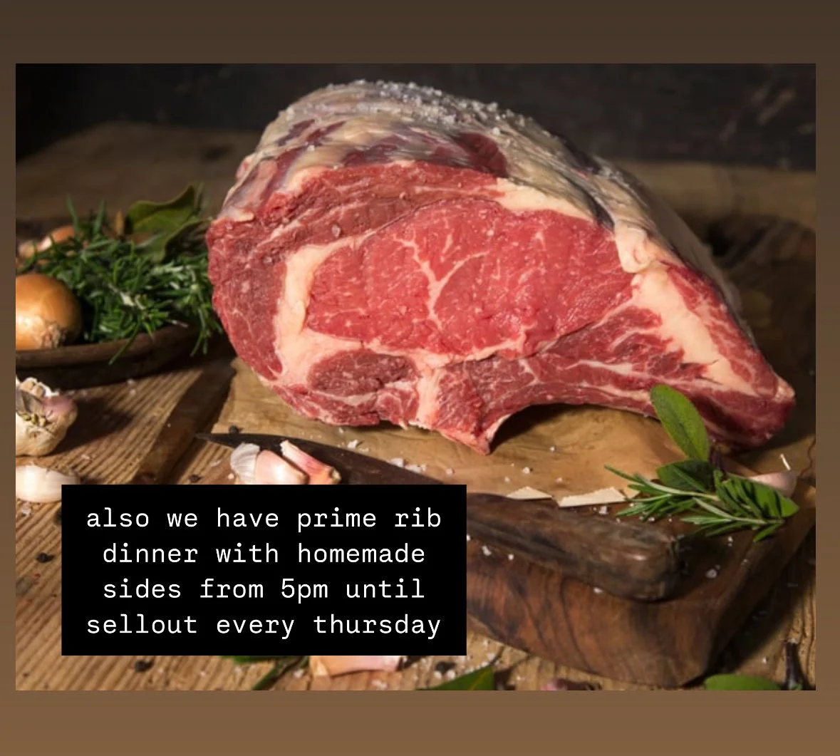 A marbled slab of prime rib on a cutting board with herbs.