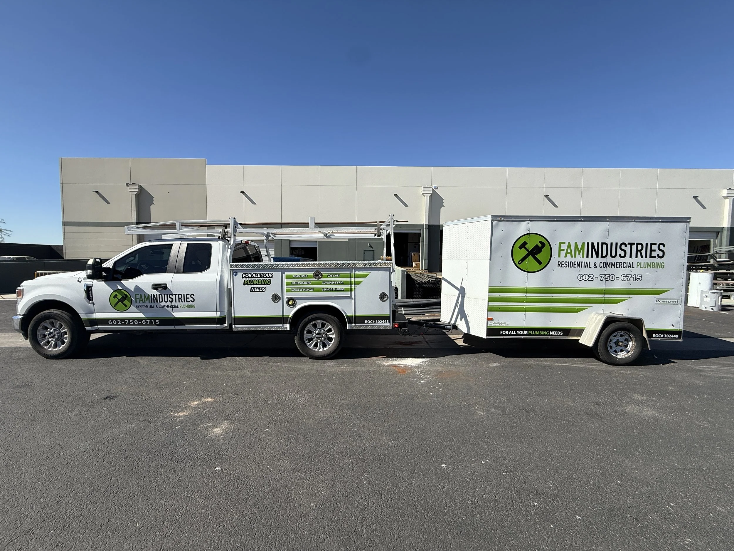 A FAM Industries plumbing service truck with a trailer attached, parked in front of a beige building under a clear blue sky.
