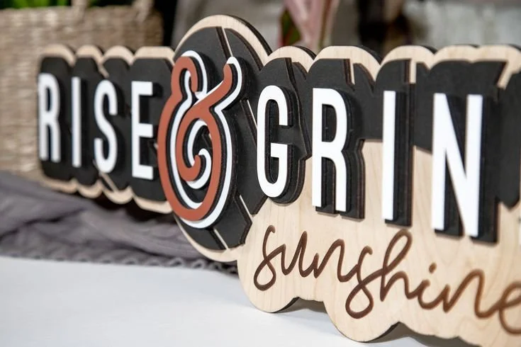 Decorative wooden signs with motivational words, including 'Rise & Grind' and 'Sunshine'.